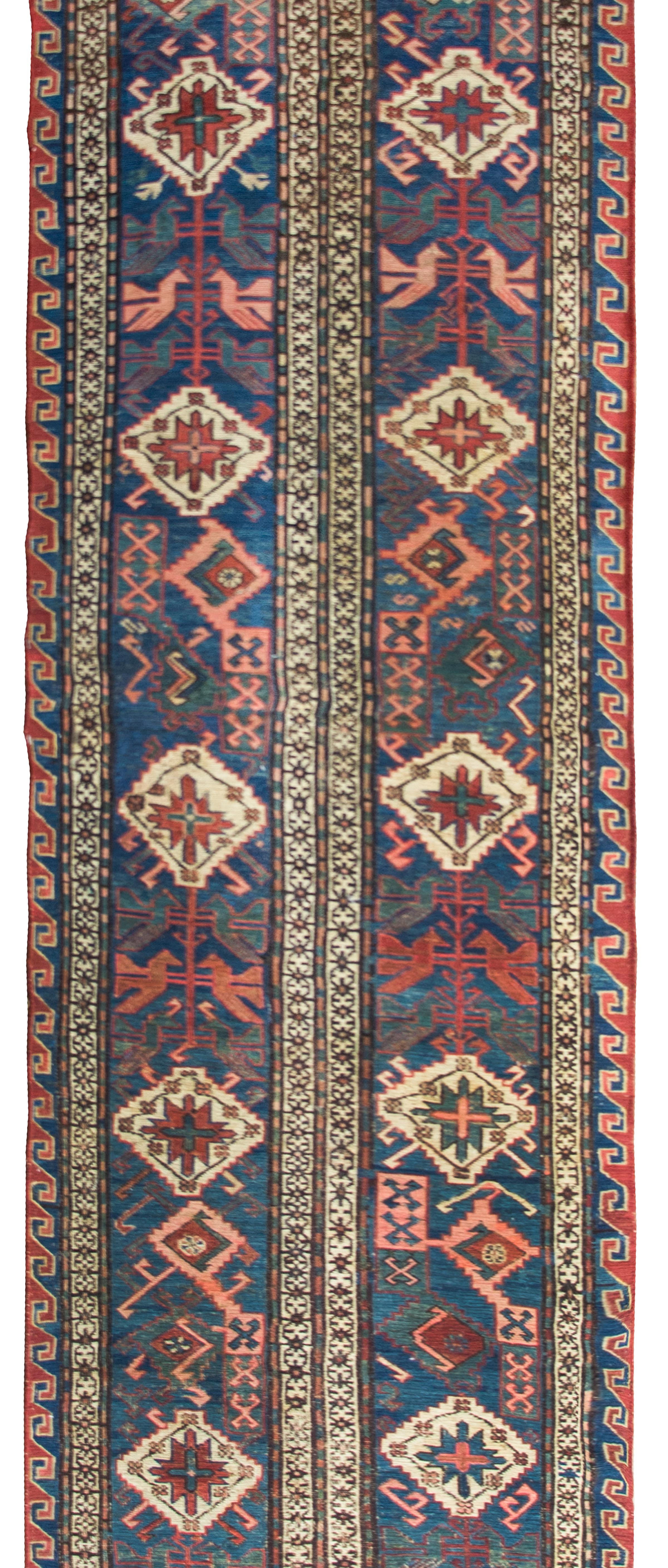 A stunning early 20th century Persian Soumak runner with the most wonderful tribal pattern with several white diamond medallions amidst a field of stylized flowers and birds, woven in pink and green, outlined in crimson stripes, and set against an