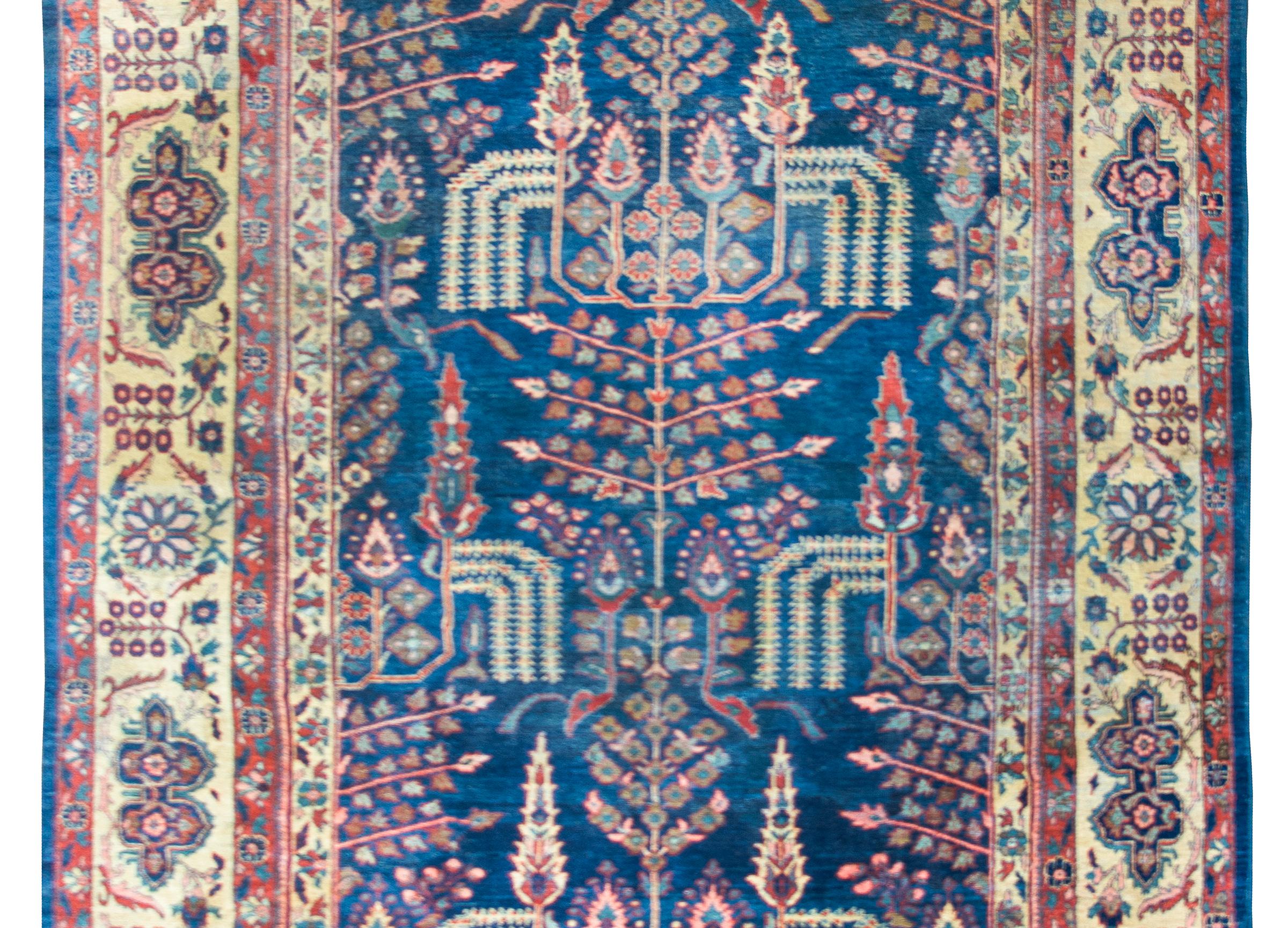 A breathtaking early 20th century Persian Sultanabad rug with a tree-of-life pattern containing a large central tree flanked by cascading willow branches, cypress trees, and myriad other floral forms.  The border is one of the best we've seen in a