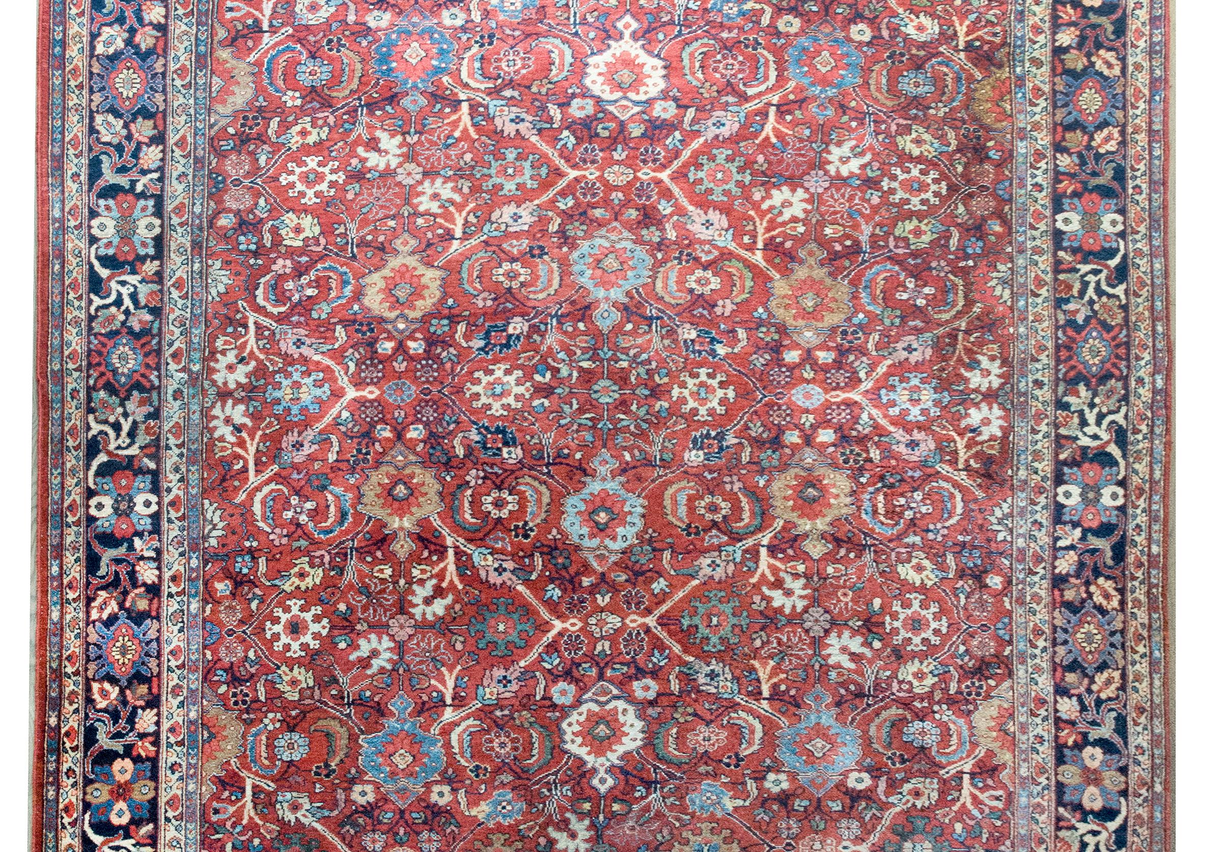Uno splendido tappeto persiano Sultanabad Rugs dell'inizio del XX secolo con un motivo floreale e di viti a scorrimento allover con grandi fiori indaco, verdi, bianchi, marroni e rosa, il tutto circondato da uno splendido bordo ripetuto con motivi