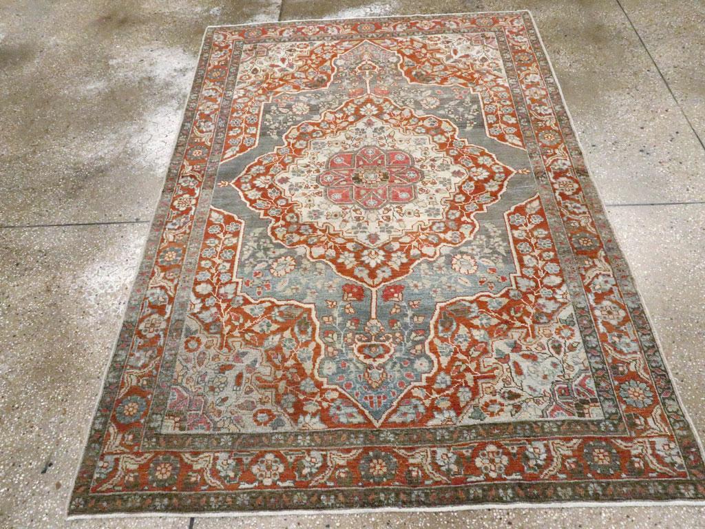 Un antico tappeto d'accento persiano Tabriz. Un sottomedaglione avorio pieno di fiori è incastonato in un medaglione pendente in mattoni insieme agli angoli del campo esteso. Il campo abrasivo sagomato di colore grigio-blu è doloroso verso i lati ma