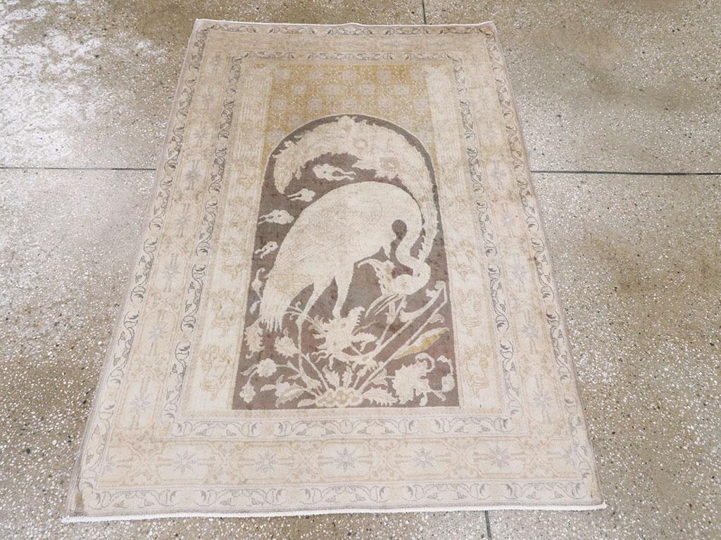 Le champ brun surmonté d'une arche présente une grue affrontant une tête de dragon émergeant d'une touffe de fleurs à la base de ce tapis oriental ancien. L'arrière-plan est occupé par des nuages. Un motif textile répétitif recouvre les écoinçons.