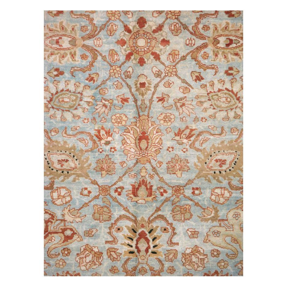 An antique Persian Tabriz room size carpet handmade during the early 20th century with a floral pattern over a light grey and light powder blue field and bordered in rust red.

Measures: 8' 3