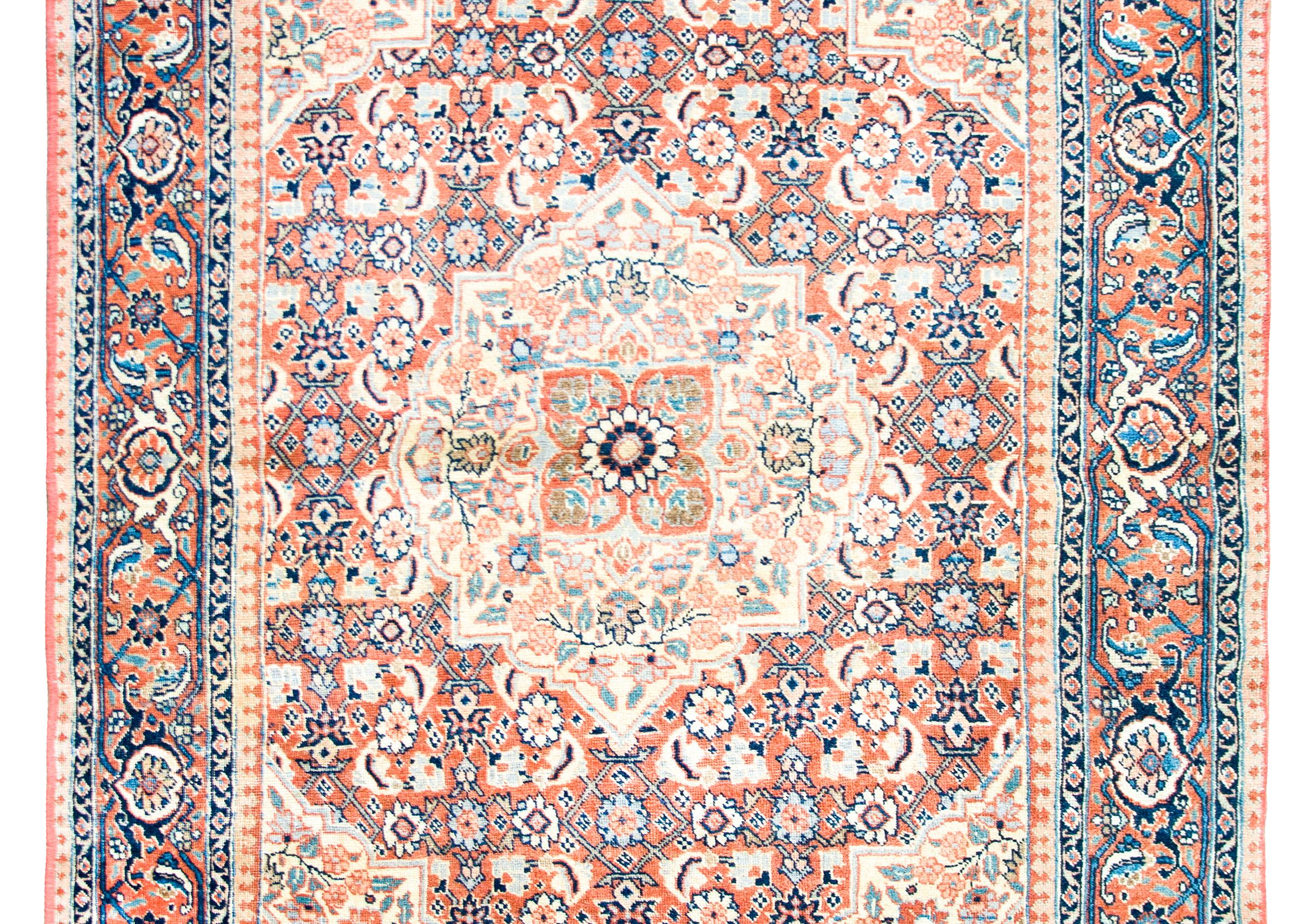A beautiful early 20th century Persian Tabriz rug with a small central floral medallion living amidst several more medallions, each with their own unique repeated floral patterns, and surrounded by a complex border with a wide central floral