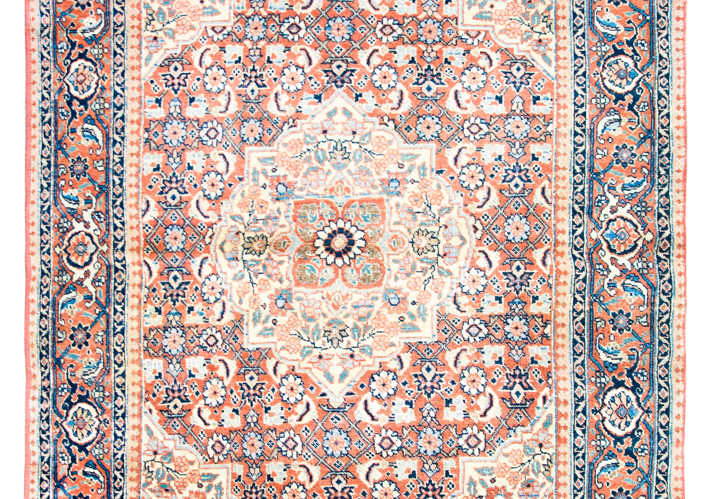Un bellissimo tappeto persiano Tabriz dell'inizio del XX secolo con un piccolo medaglione floreale centrale che vive in mezzo a diversi altri medaglioni, ognuno con i propri motivi floreali ripetuti, e circondato da un complesso bordo con un'ampia