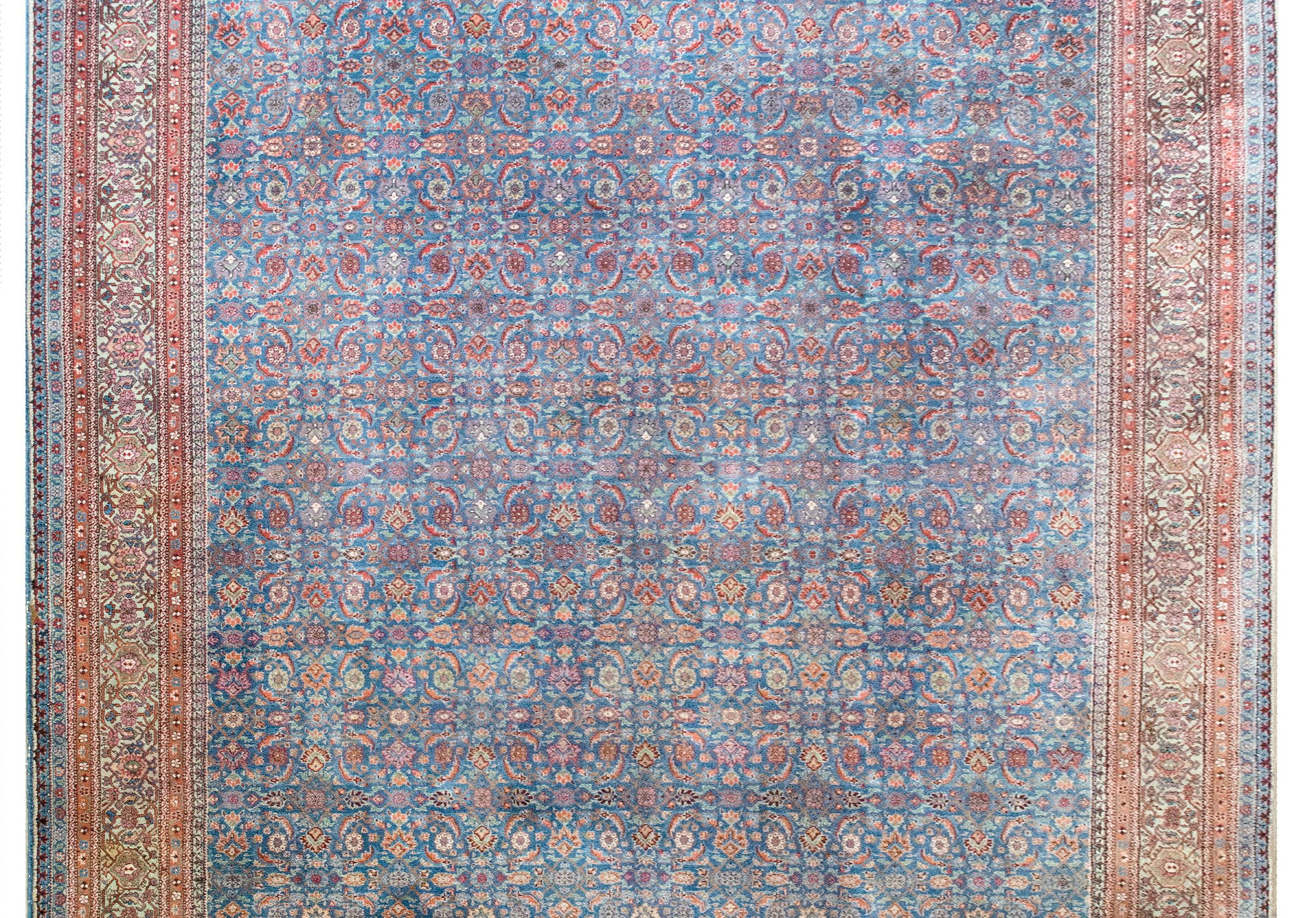 Uno splendido tappeto persiano tabriz dei primi del Novecento con un meraviglioso motivo a traliccio floreale a specchio con una miriade di fiori e foglie sul fondo, circondato da un complesso bordo con più coppie di sottili strisce a motivi