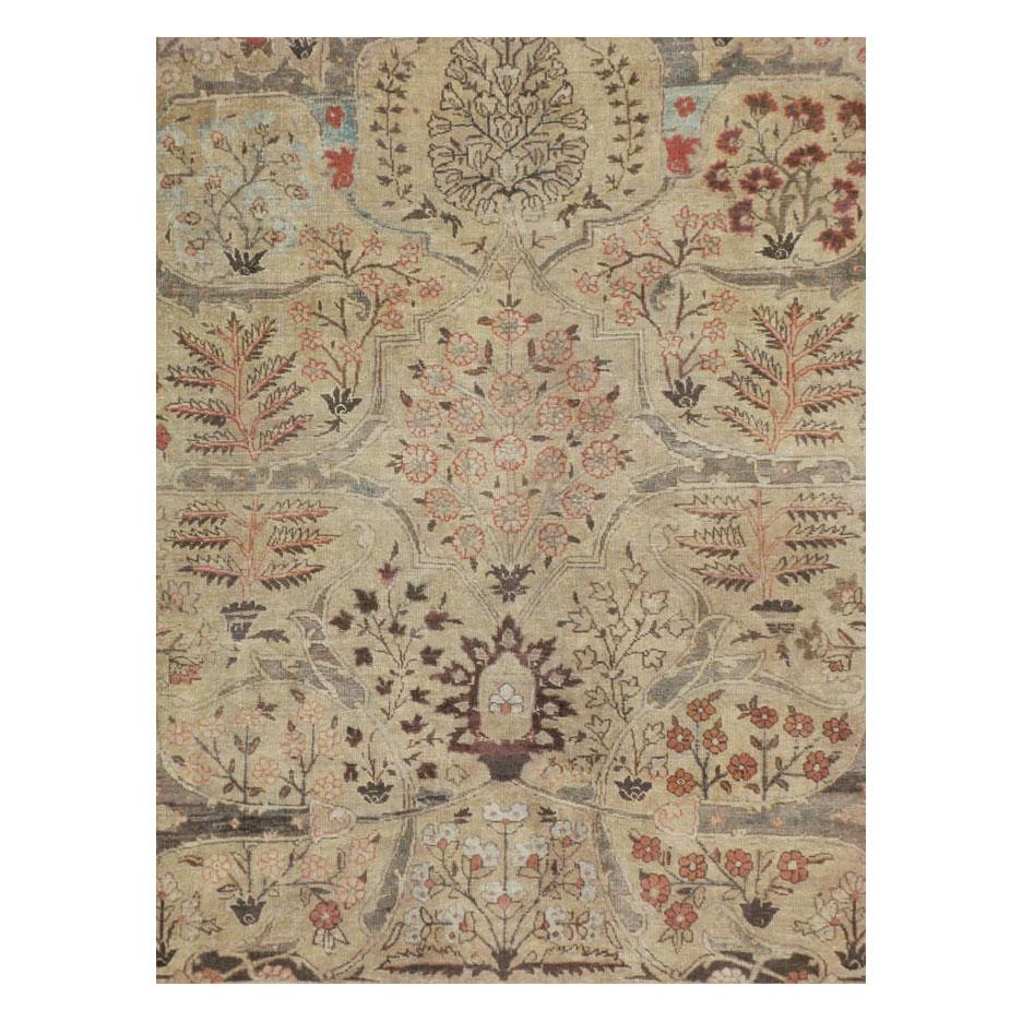 Un antico tappeto persiano Tabriz di piccole dimensioni realizzato a mano all'inizio del XX secolo. Il disegno floreale è suddiviso uniformemente lungo ciascun lato dell'asse centrale su un campo marrone chiaro decorato con un arabesco su larga