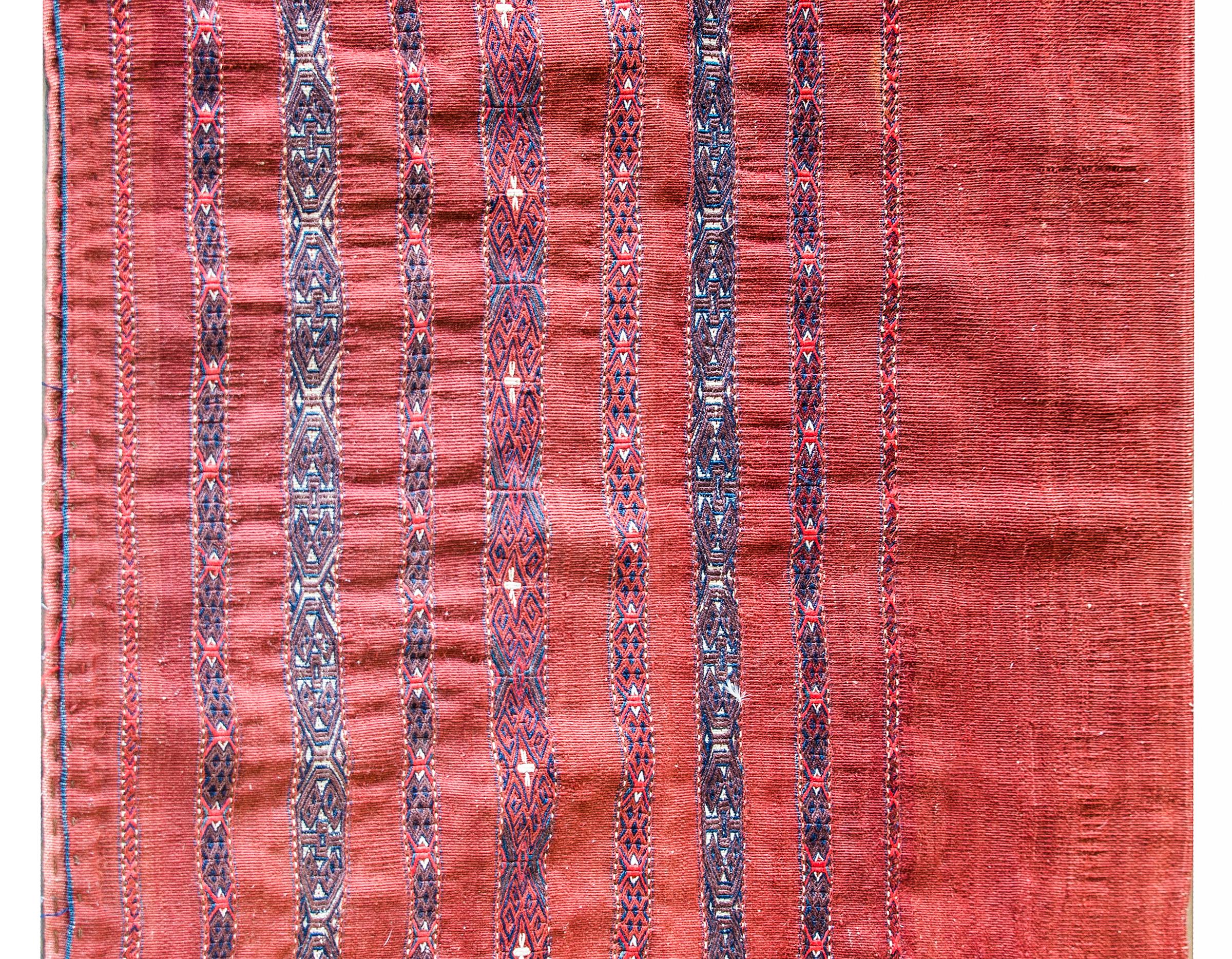A wonderful early 20th century Persian Turkman bag face rug with a simple crimson ground with tightly woven geometric patterned stripes woven in indigo, crimson, and brown.