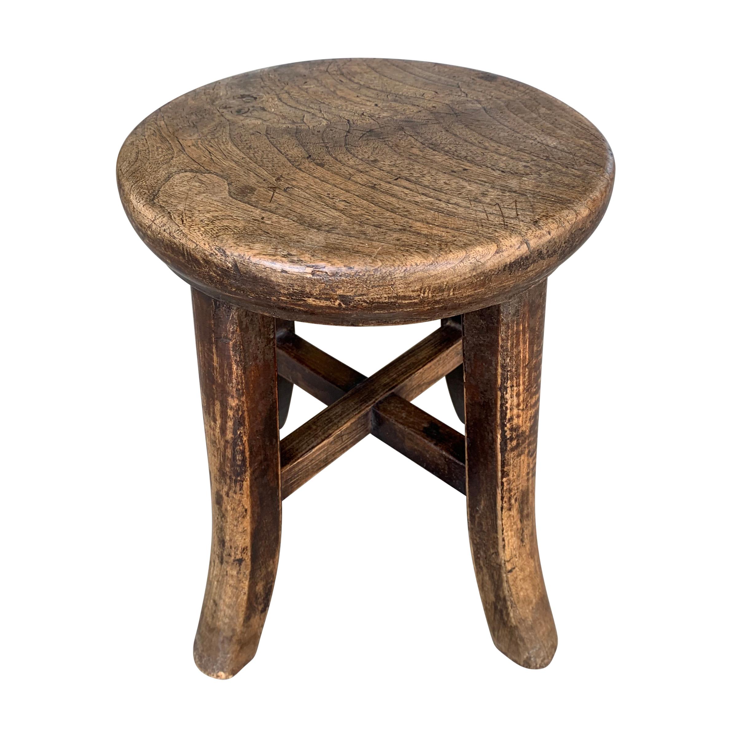 An early 20th century petite Chinese elmwood stool with legs ending in cute flared feet. The top is one solid piece of wood with rounded edges. Also serves as a small drinks table next to a low sofa or chair.