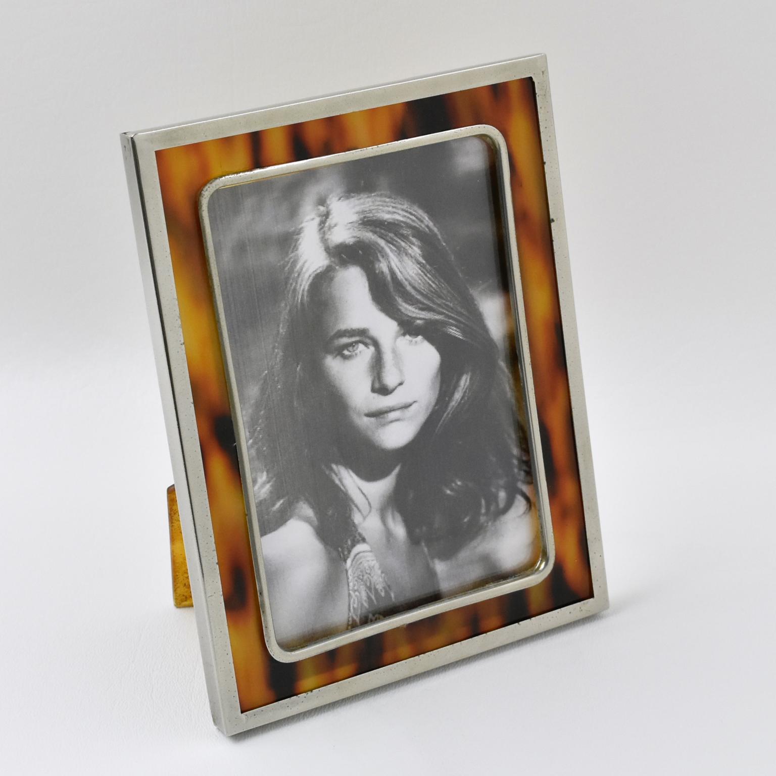 Early 1920s picture photo frame. Imitation tortoiseshell pattern celluloid with chromed metal framing. Back and easel in same celluloid material with the same pattern. Marked on the easel: Made in Spain.
Measurements:
Overall: 4.75 in. wide (12