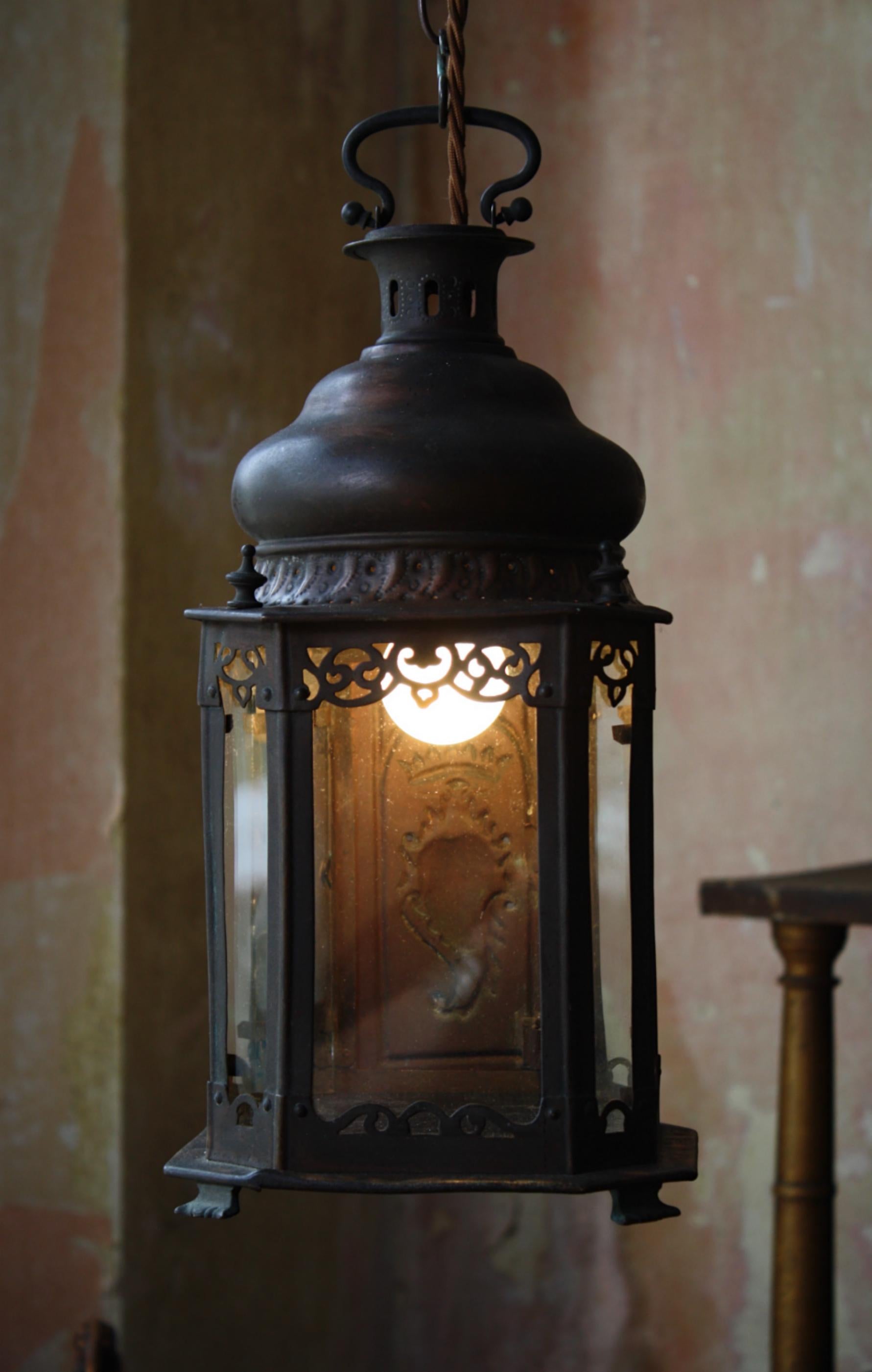 A diminutive copper devotional lantern, used within the catholic household. 

Constructed from pierced and pressed copper, a hinged door with a pressed sacred heart adorns one side with the remaining three being clear glass and a stained deep blue