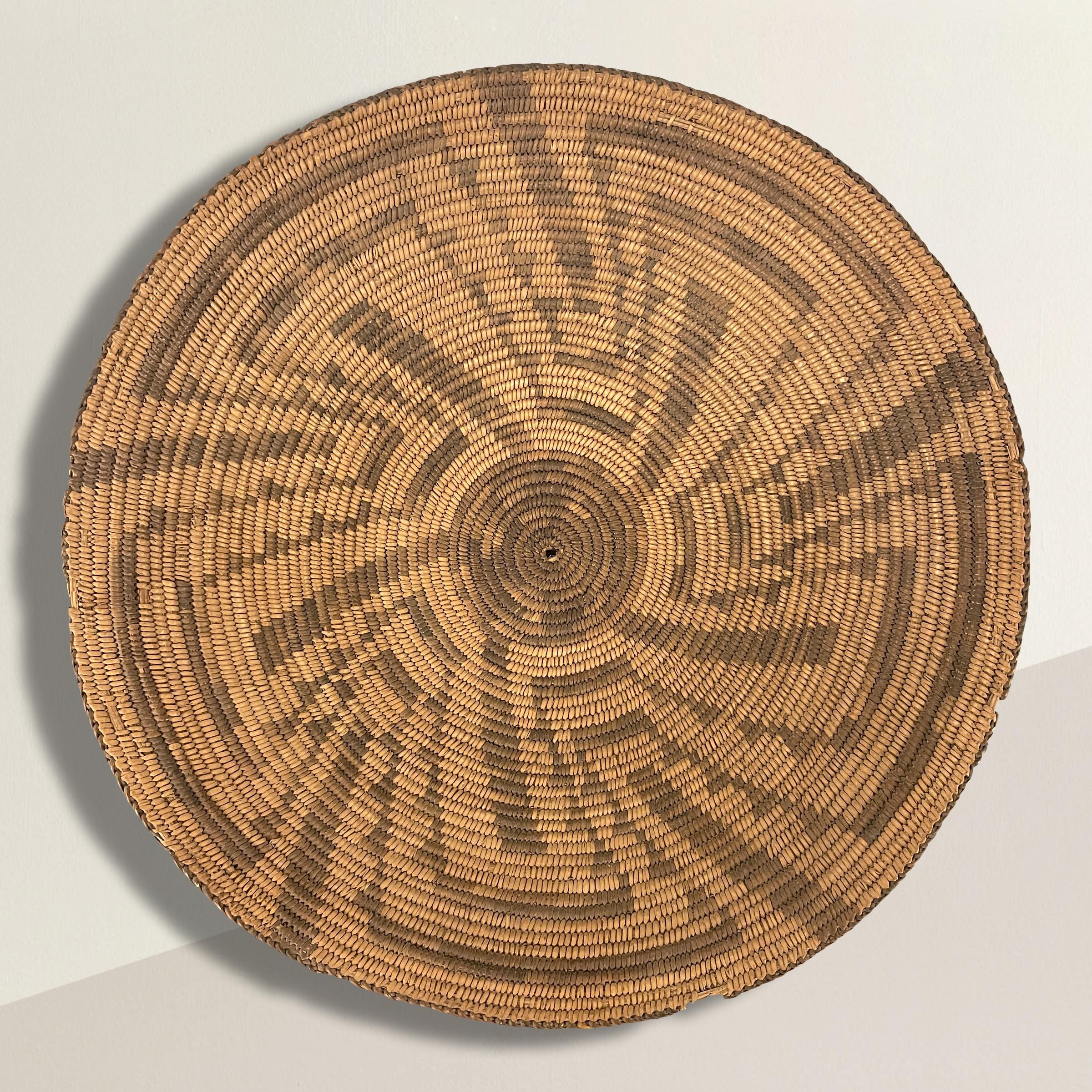 A bold and impressive early 20th century Native American Pima hand-woven willow and devil's claw basket with a five-pointed swirling star in the center with meandering motifs radiating from the star.