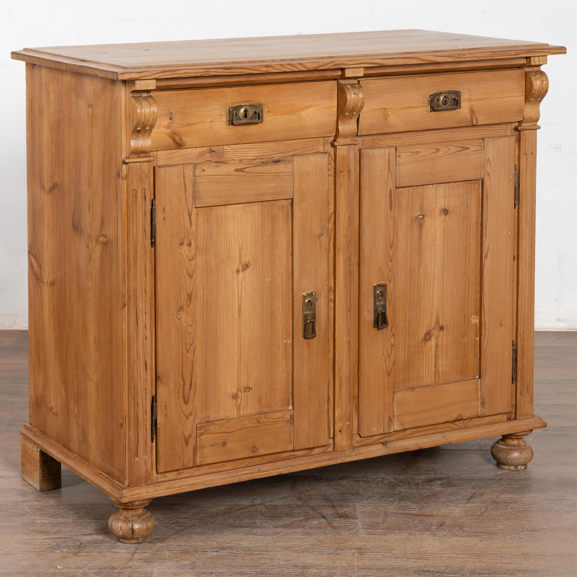 Credenza antica in legno di pino con ante a pannello, dettagli laterali intagliati e sollevata su piedini a cono. Due cassetti su due ante.
Restaurato e lucidato a cera, questo mobile è stabile, robusto e pronto per l'uso. Funzione dei cassetti. Le
