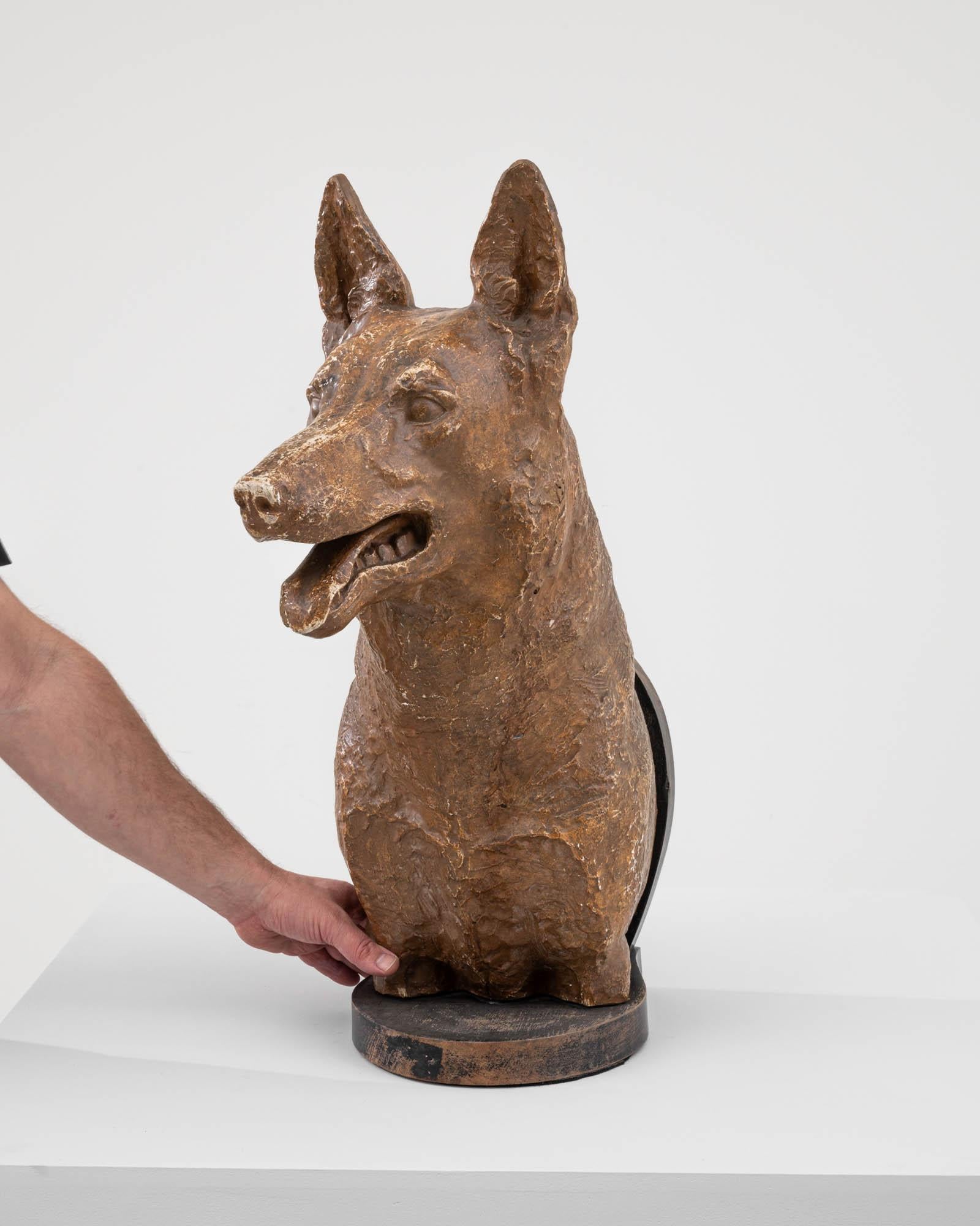 This Early 20th Century Plaster Dog Sculpture exudes a certain nobility and charm. Crafted with attention to detail, the sculpture showcases a faithful canine with a poised and alert expression. The plaster material allows for fine textural details,