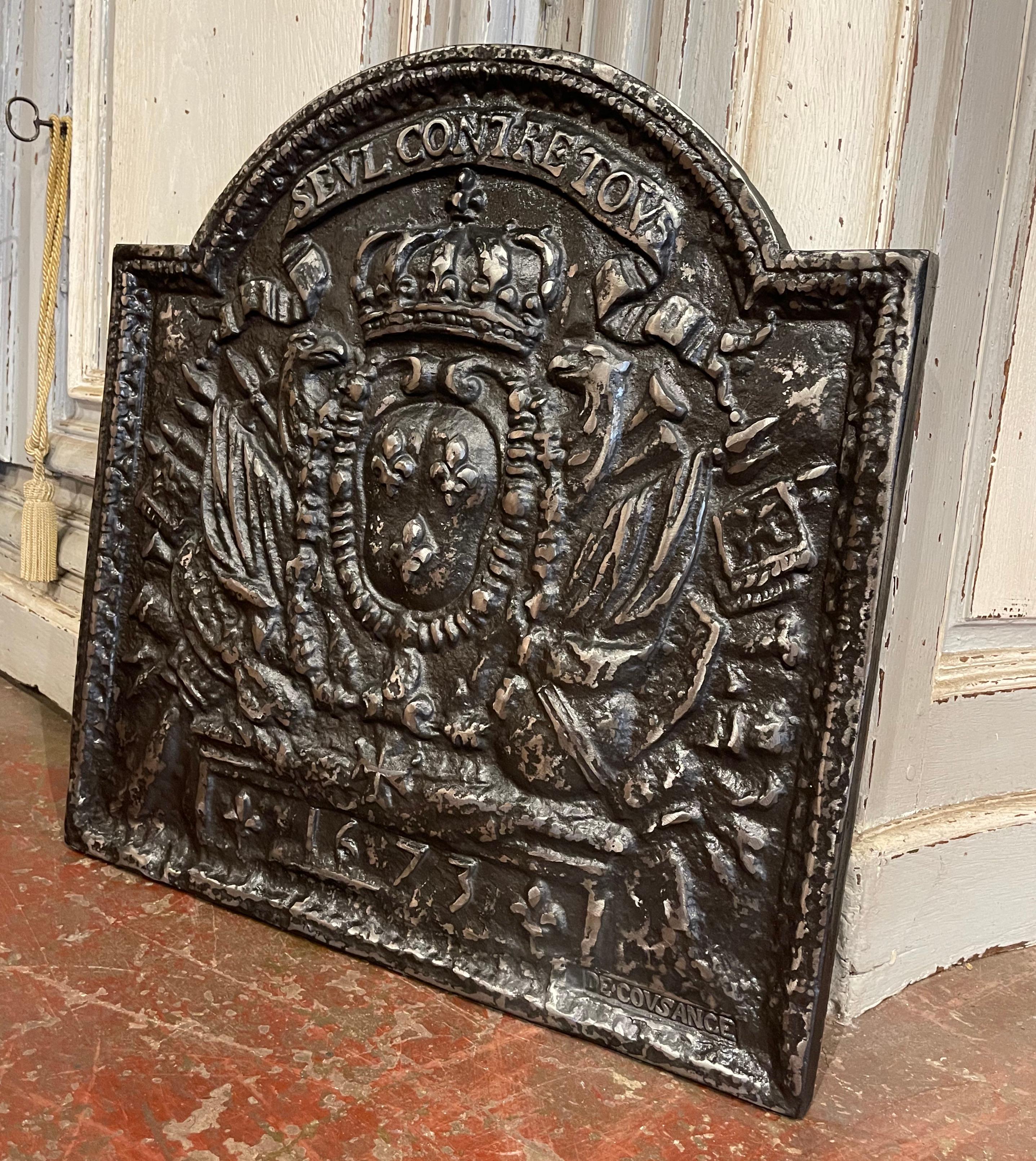 Decorate your fireplace or kitchen back splash with this elegant antique fire back. Crafted in France circa 1920 and almost square in shape, the ornate arched fireplace essential features a center medallion with the Royal Arms of France after