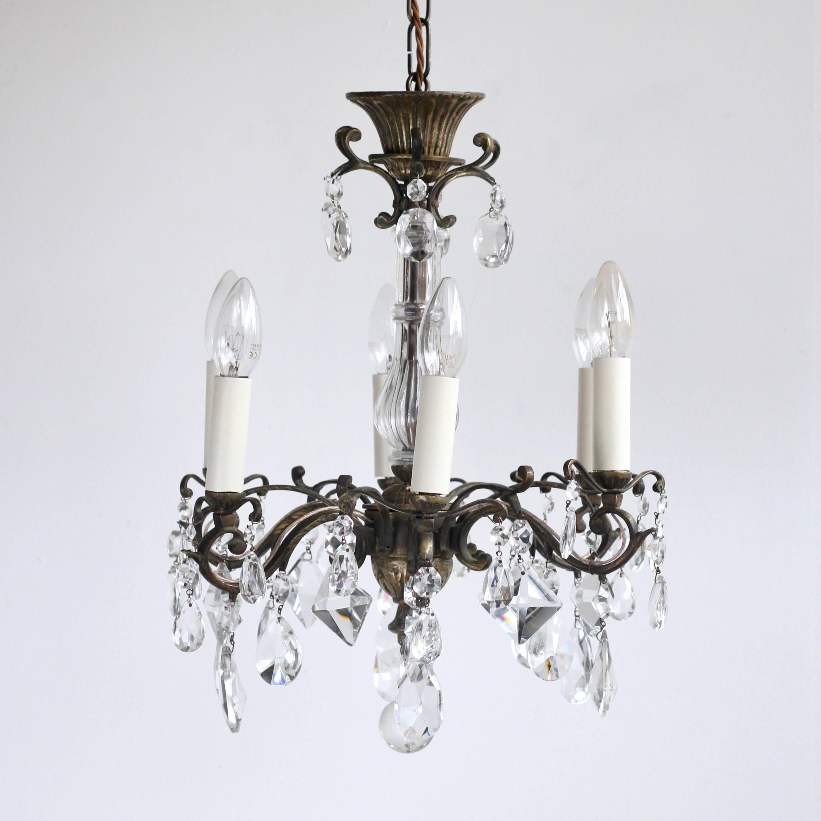 This pretty French chandelier is an excellent example of a quality early 1900s brass and crystal chandelier. The brass frame is beautifully elegant with a simple design with added decorative pieces that are understated yet refined. There is a glass