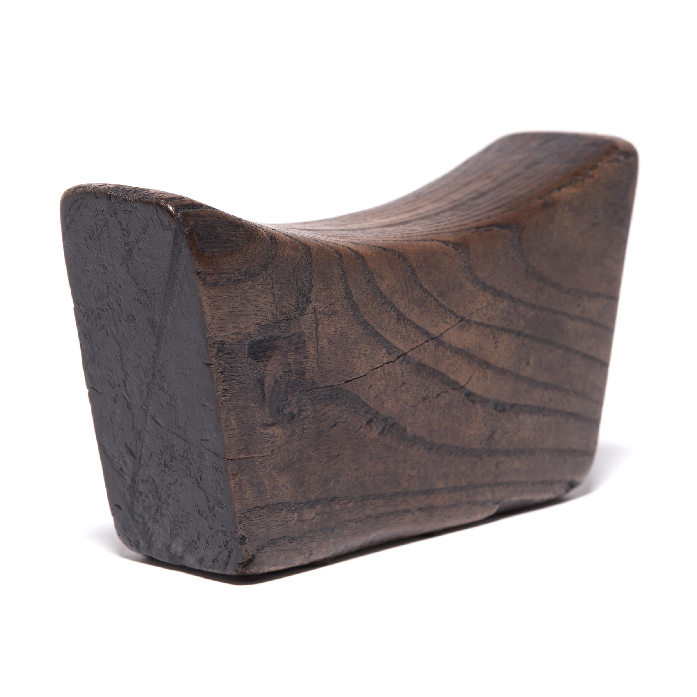 Made of Chinese northern elmwood, this smooth block of wood was once used by an upper-class woman as a headrest. The soft curve and height of the block not only supported her head and neck at rest, it also helped to preserve her intricate hairstyle.