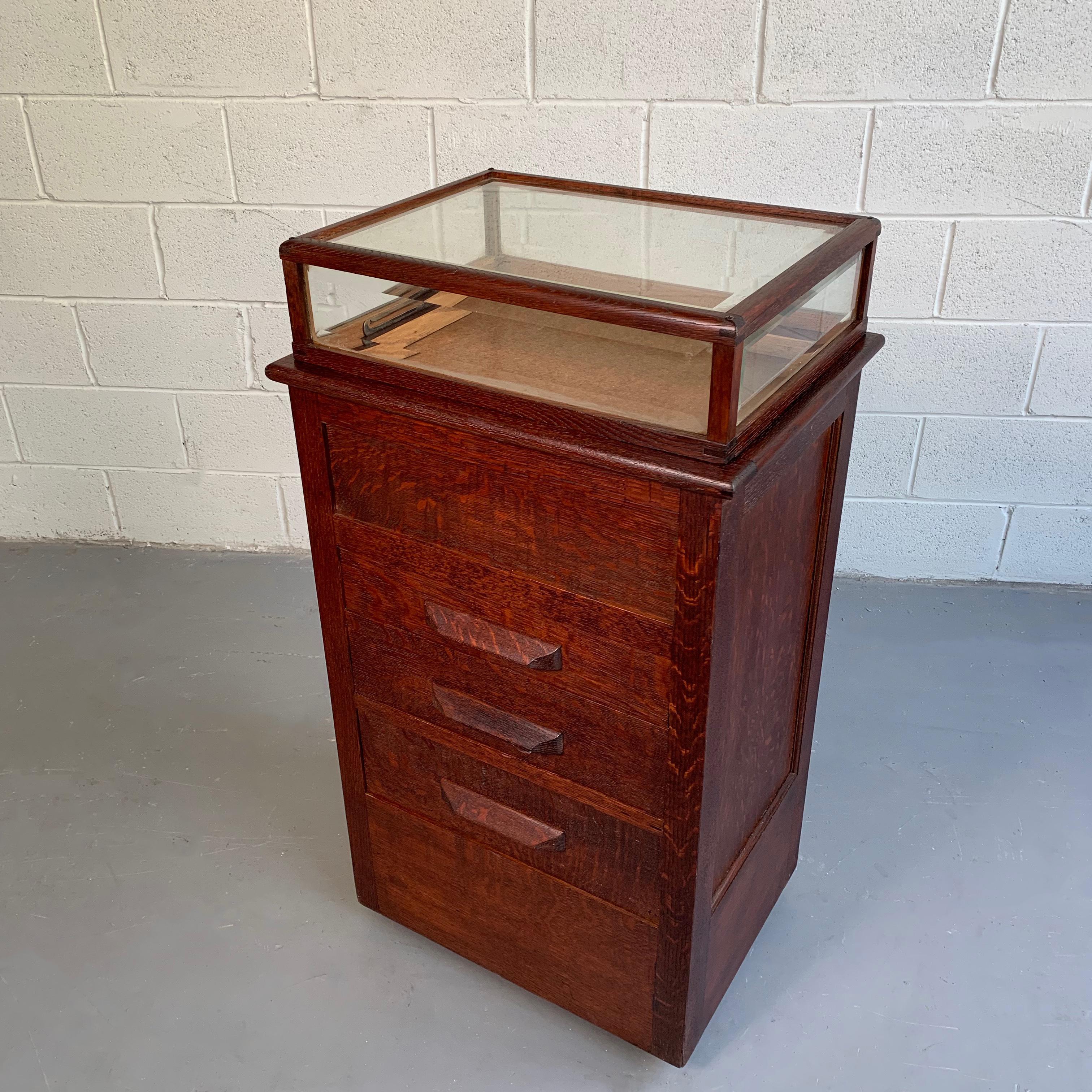 Early 20th century, watch or jewelry display case features a quarter sawn oak, 3 drawer cabinet on the bottom and a beveled glass vitrine on top. The bottom drawers are 6, 4.5 and 4 inches in height. Finished on all sides.
