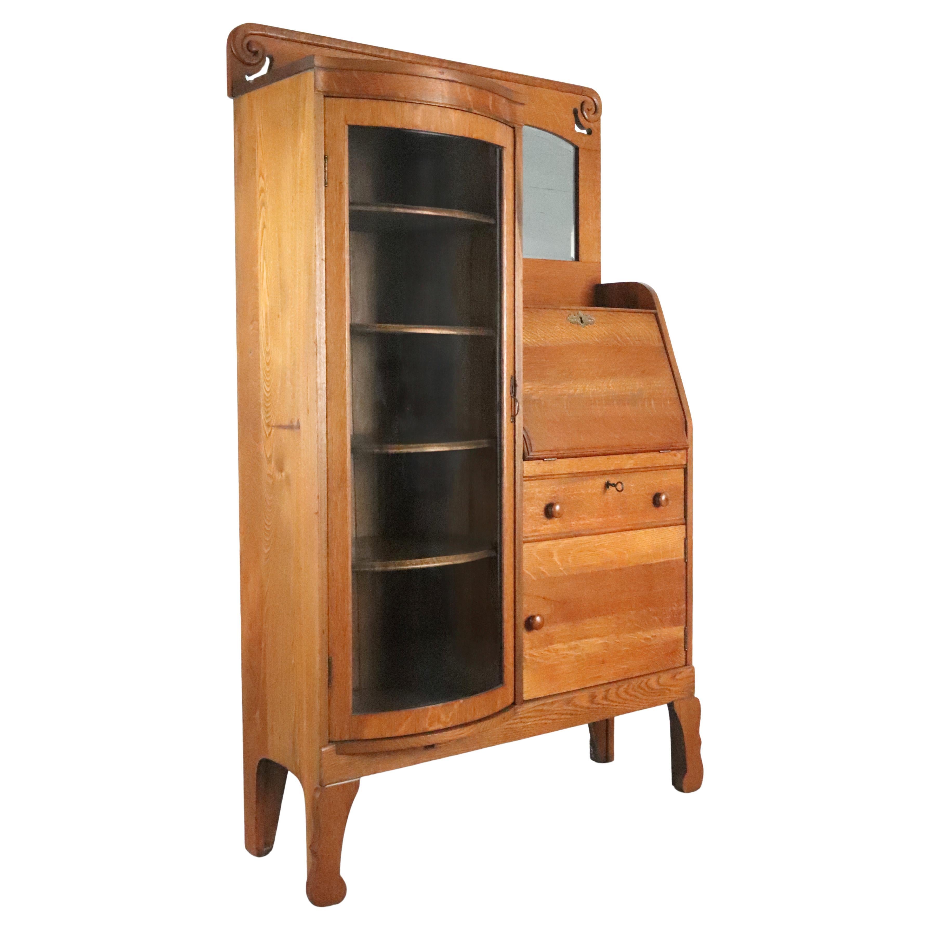 Antique oak side by side cabinet in a medium tone stain. On the left side, there is a curved silvered glass door curio cabinet with the original four adjustable wood shelves. On the right side, there is a beveled mirror above, followed by a