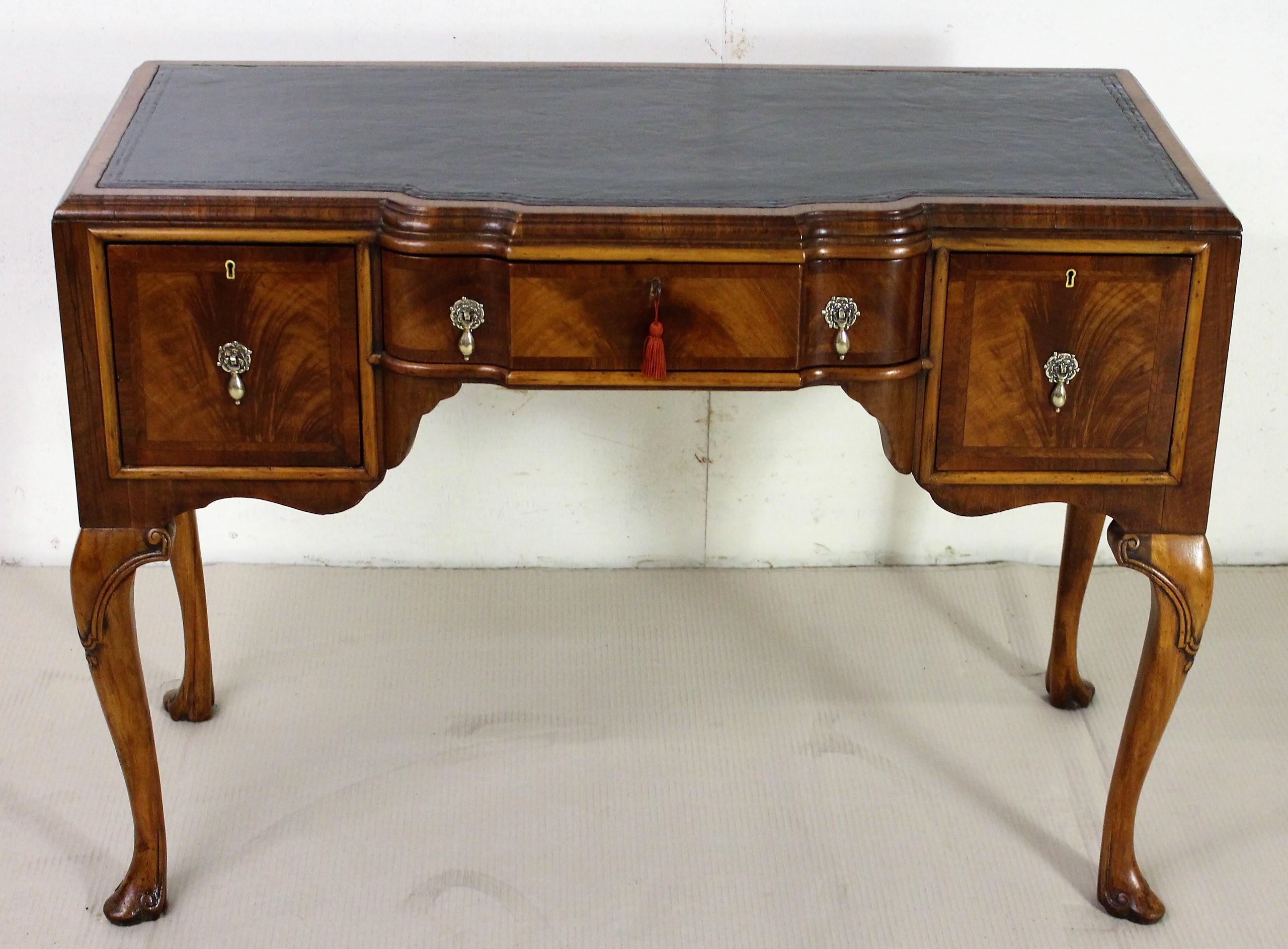 A charming burr walnut writing table in the Queen Anne style. Well constructed in solid walnut with attractive burr walnut veneers. The top fitted with a sumptuous black leather writing surface with blind tooled detailing to the edges. There is an