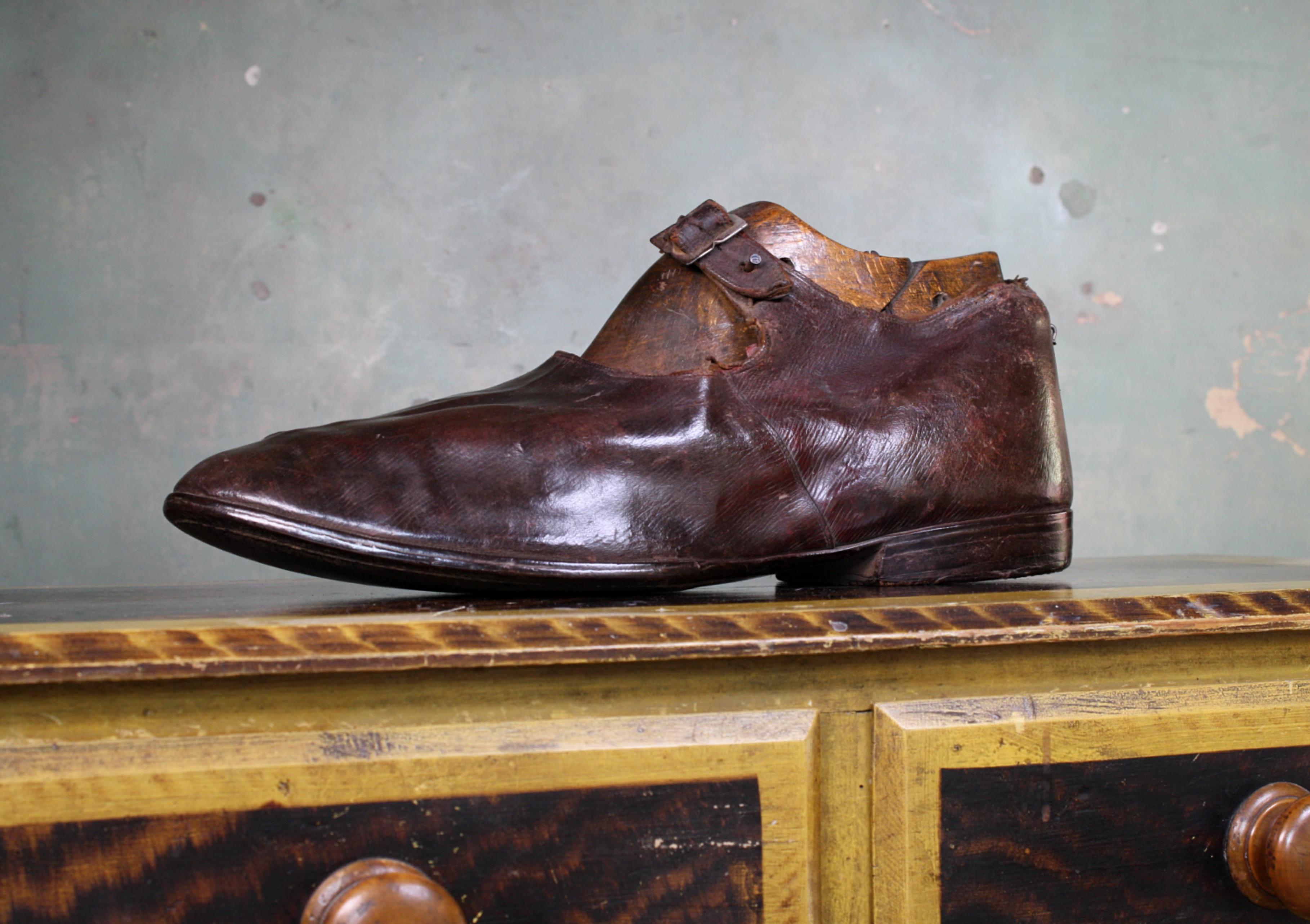 An odd decorative item, by repute the shoe of Russian Giant Feodor Machnow.

The shoe is of leather construction, maroon in color, with a brass buckle. Leather sole and heal, the shoe has been well worn due to the consistence wear especially on