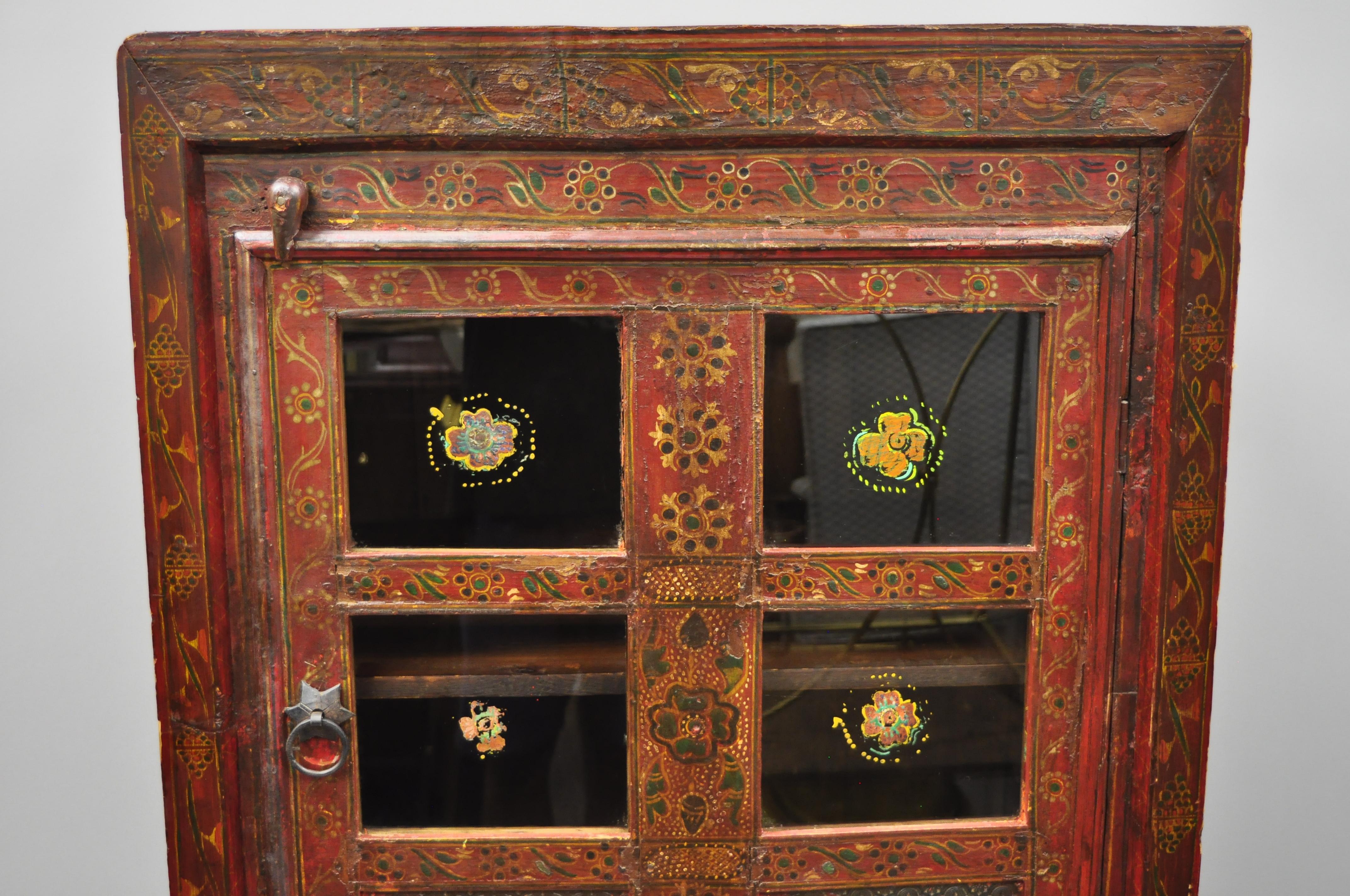 Early 20th century red painted Mongolian / Tibetan Boho cupboard cabinet. Item features glass panes, floral painted accents, solid wood construction, one swing door, three drawers, great style and form, top and sides are unfinished, circa early 20th