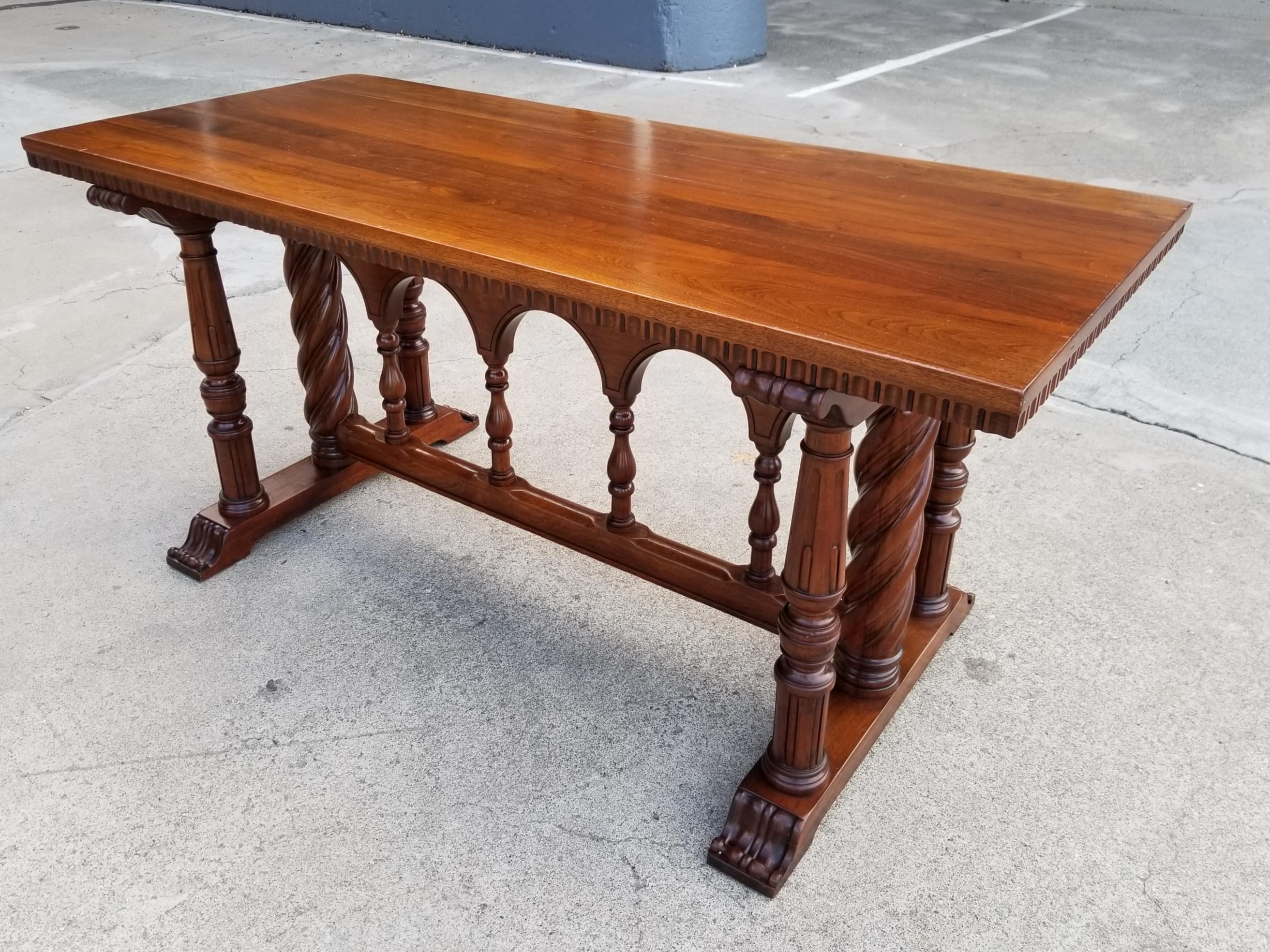 Not often do you find furniture crafted entirely of solid walnut! This early 20th century refectory or library table has remarkable craftsmanship. Classic Spanish Revival design with turned wood columns and arched center support. This piece might