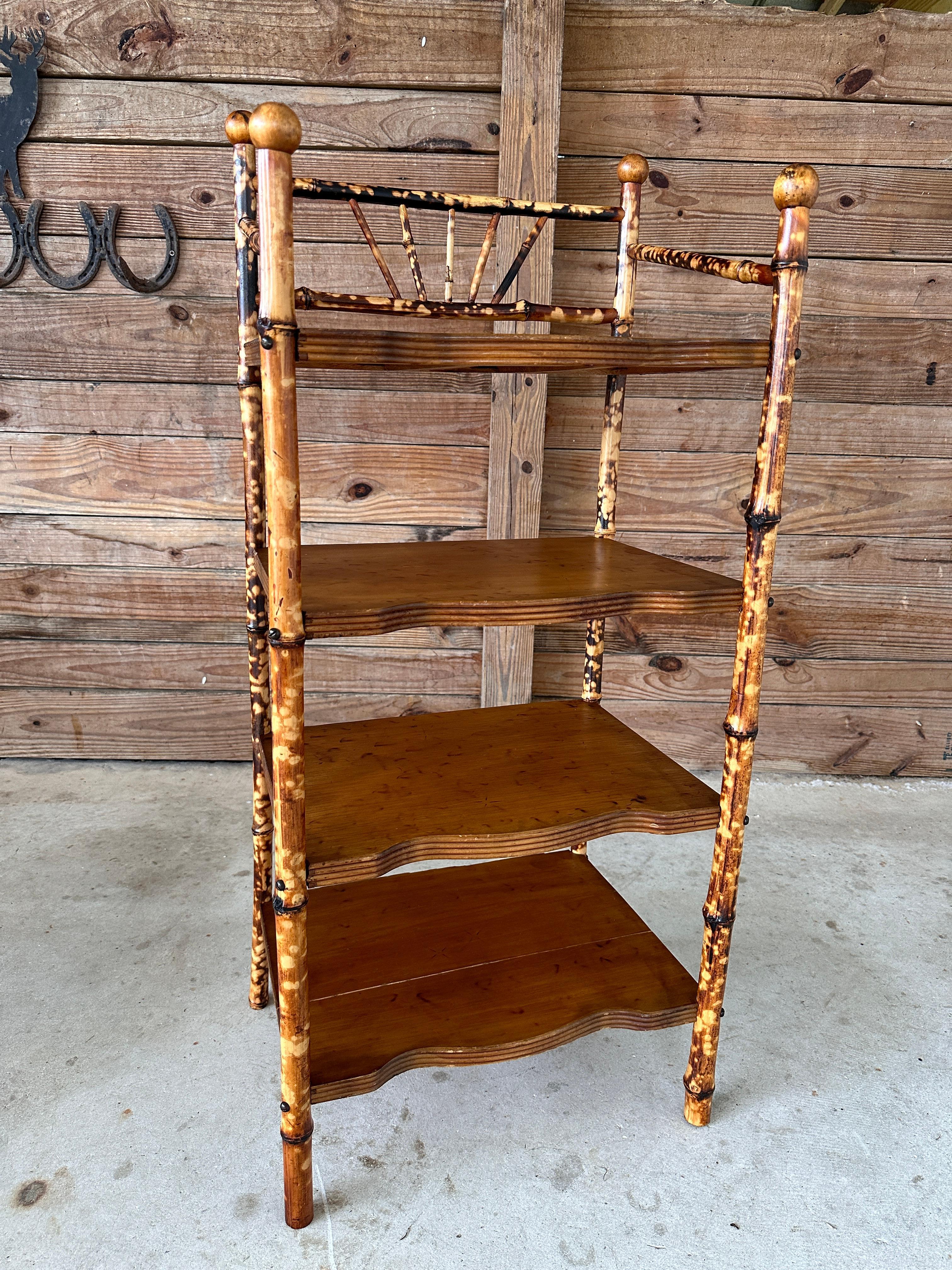 Early 20th Century English scorched bamboo shelf, meticulously refinished and restored while preserving its antique charm.
This beautiful four-tiered shelving unit showcases an intricate bamboo frame with its characteristic scorched finish, offering