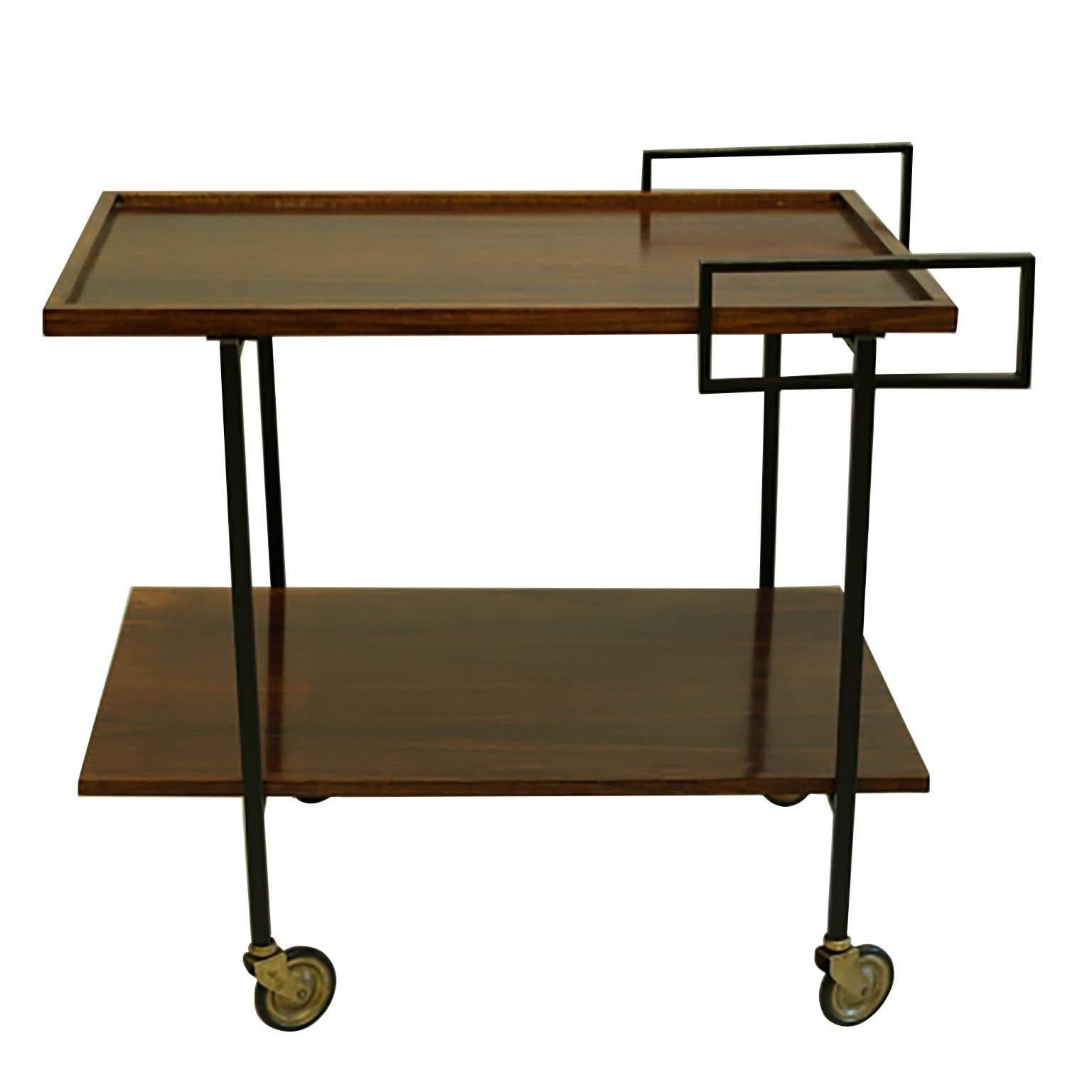 ABOUT

This is an original mid-century bar cart. The bar cart has two Rosewood shelves supported by ebonized, brass legs and handles with brass and rubber wheels. The piece has retained its original finish and has the appropriate patina consistent