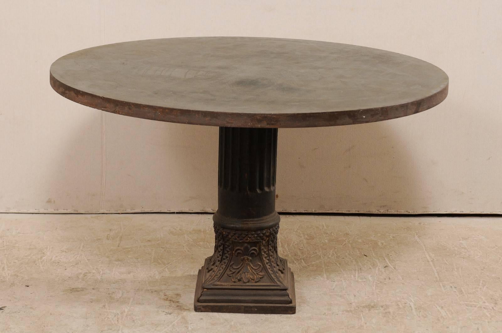 A custom American round-shaped centre table with early 20th century column pedestal base. This American table features an artisan-crafted 4 ft. diameter patinated steel wrapped wooden top which is supported by an early 20th century metal fluted