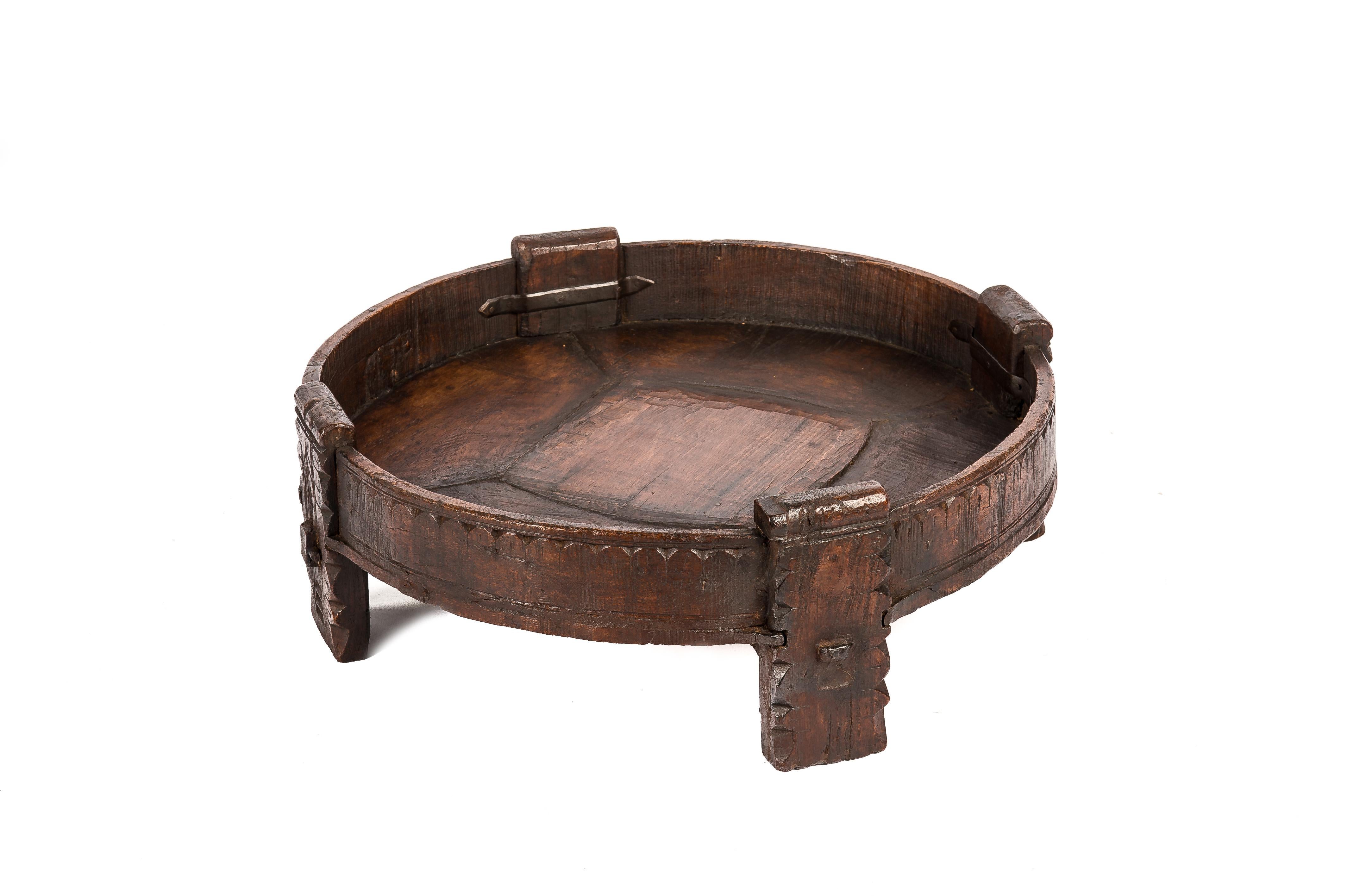 This beautiful hand-carved solid teak Grinder or Chakki table was made in India circa 1910. The table was richly decorated with hand-carved geometric details throughout the table. The piece is sturdy with reinforcing iron straps joining the legs to