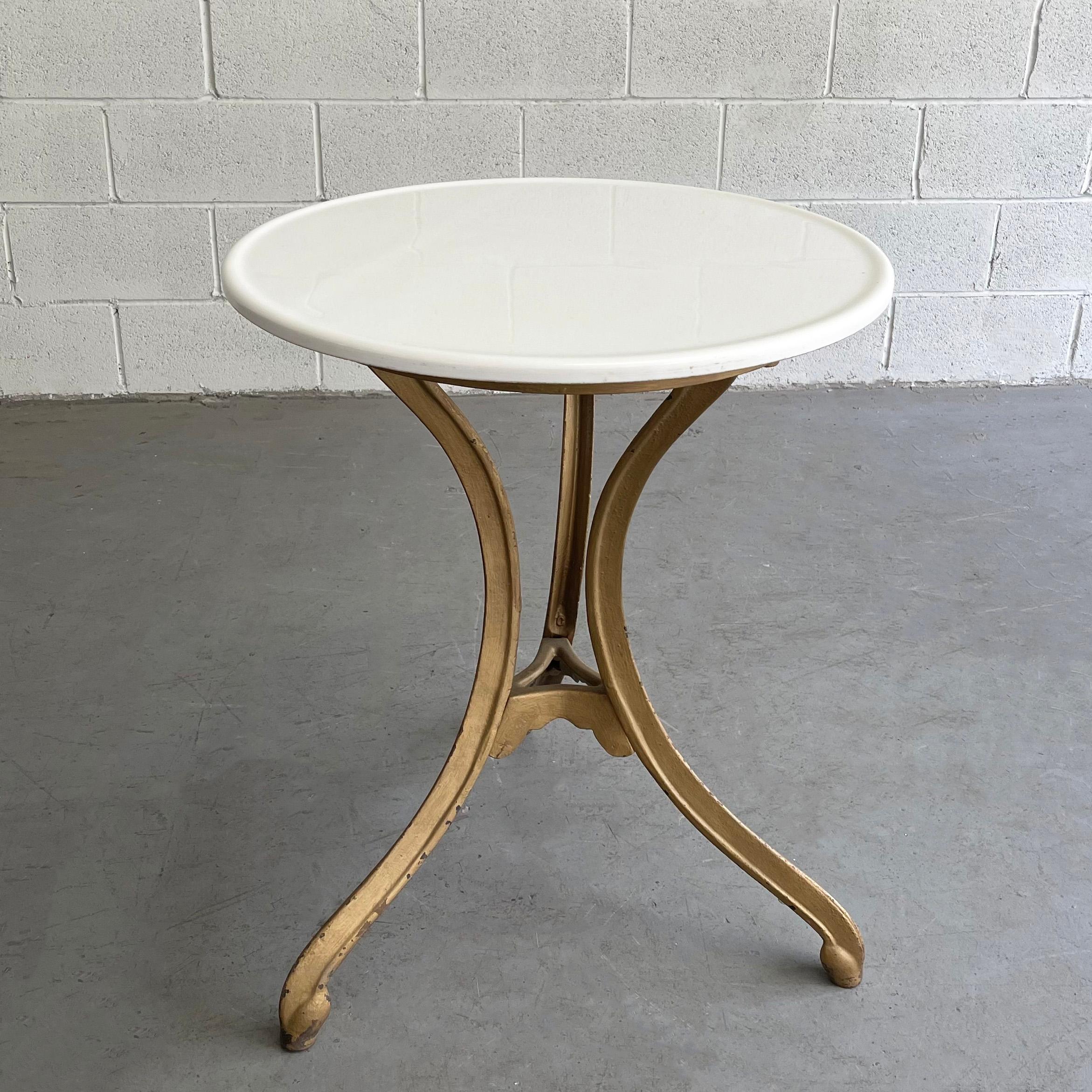 Early 20th century, café bristro table features a 24 inch round, white Vitrolite glass top with raised edge and elegant, painted cast iron base.