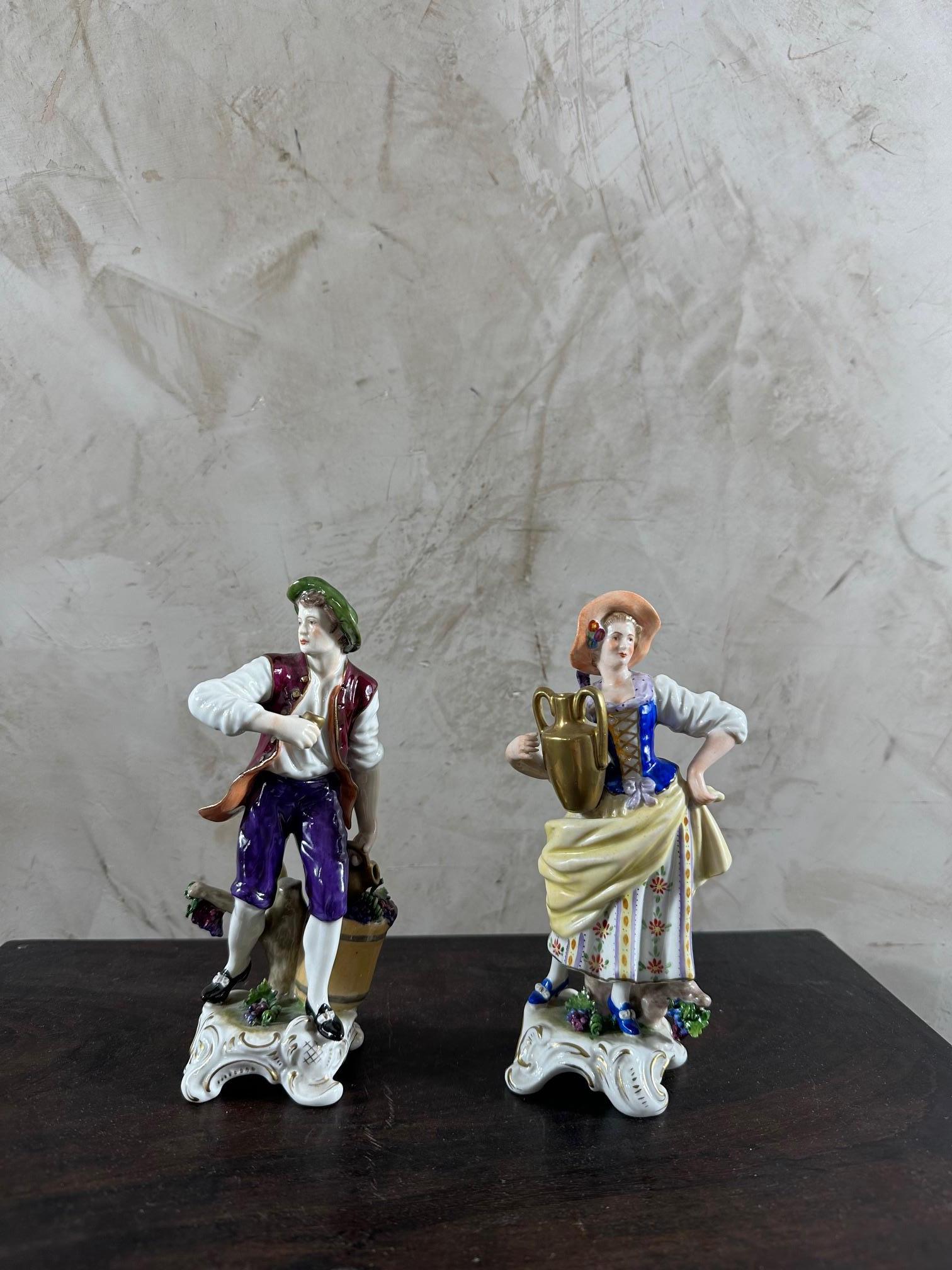 Beautiful pair of porcelain figurines representing two characters dressed in beautiful, brightly colored clothes. The man carries a seal in his hand and the woman a jug of wine. These two figurines have a signature underneath which represents the