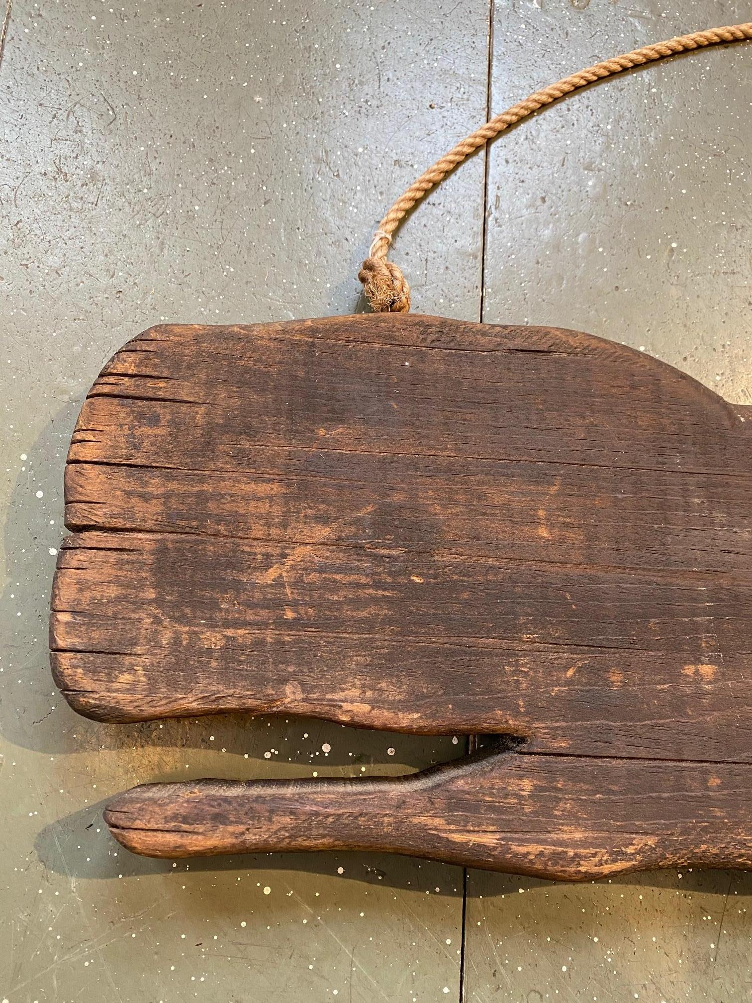Early 20th century rustic carved wooden whale, circa 1910 or so, a rough hewn thick solid plank hand cut as a sperm whale with raised flukes and mouth agape. The tail in particular is well carved, albeit in a simple style, with good curves giving a