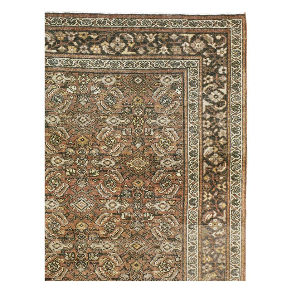 An antique Persian Malayer carpet handmade during the early 20th century. This rustic carpet employs the classic Persian 'Herati' pattern of curved lancet leaves surrounding rosettes and lozenges. Often called the 'Mahi (fish)' pattern because