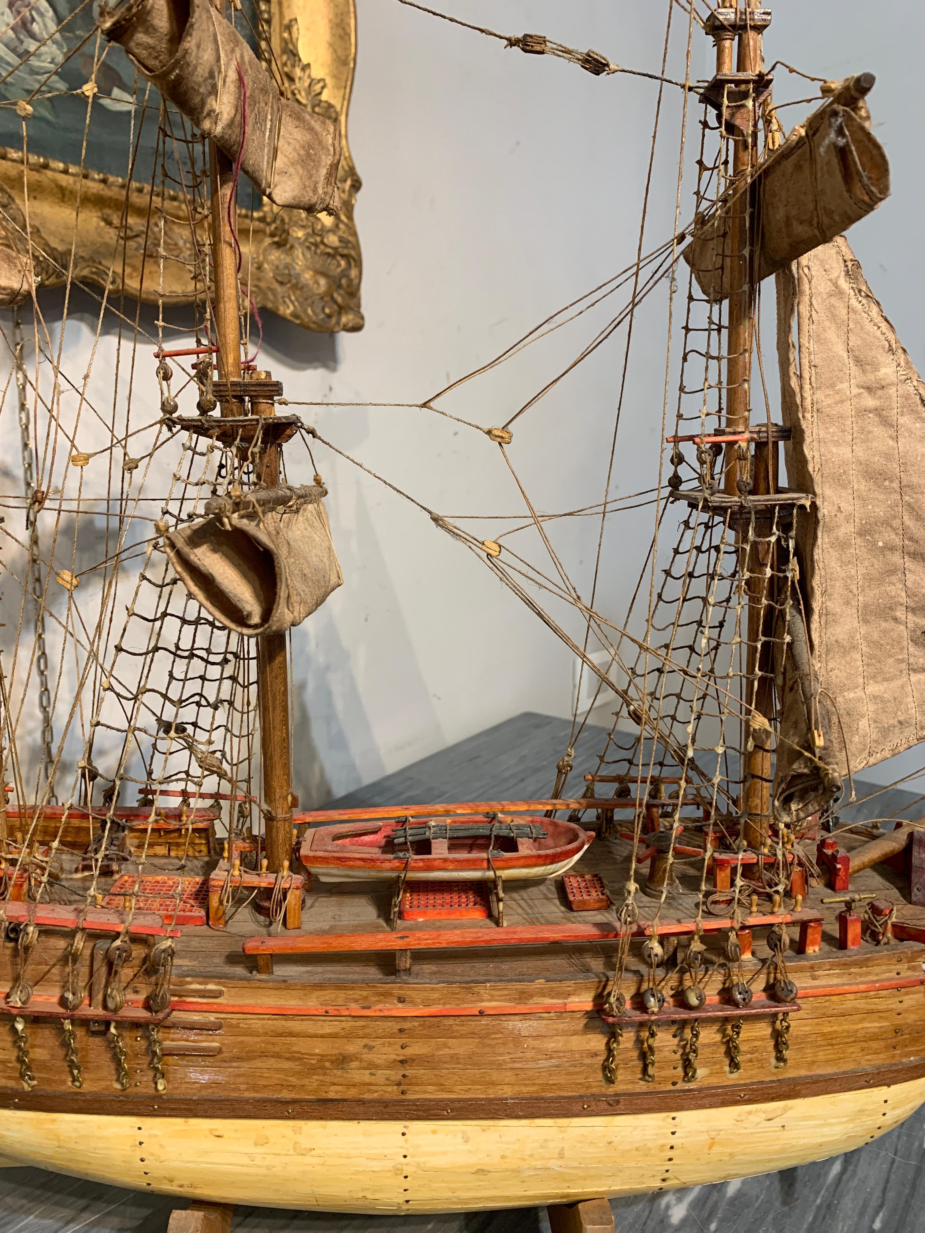 Kleines Modell eines Segelschiffs, das das berühmte englische Handelsschiff HMS Bounty darstellt. Das Modell und seine Details sind mit großer Sorgfalt und Raffinesse handgefertigt (Rettungsboot, Seile, Segel, Anker). Das Modell kann auf eine