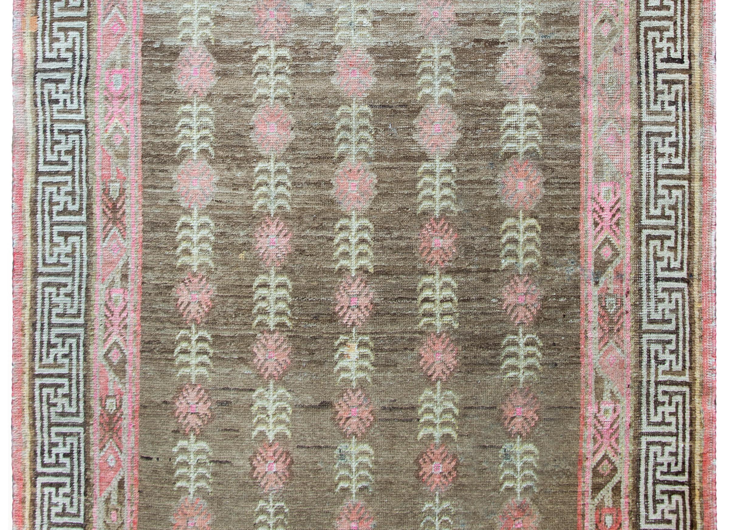 An incredible and rare-patterned early 20th century Central Asian Samarghand rug with a striped tree-of-life pattern with large pink flowers and cream stems and leaves set against a brown background, and surrounded by a complex border with an outer