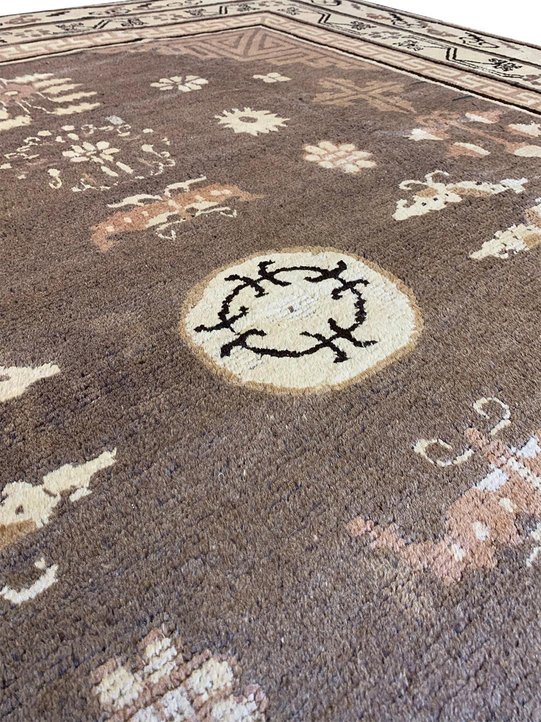 This traditional handwoven Samarkand Khotan rug has a shaded fox-brown field scattered with auspicious symbols around an ivory central roundel, the key-pattern spandrels, in an ivory double border of angular flowerhead and floral vine and cloud