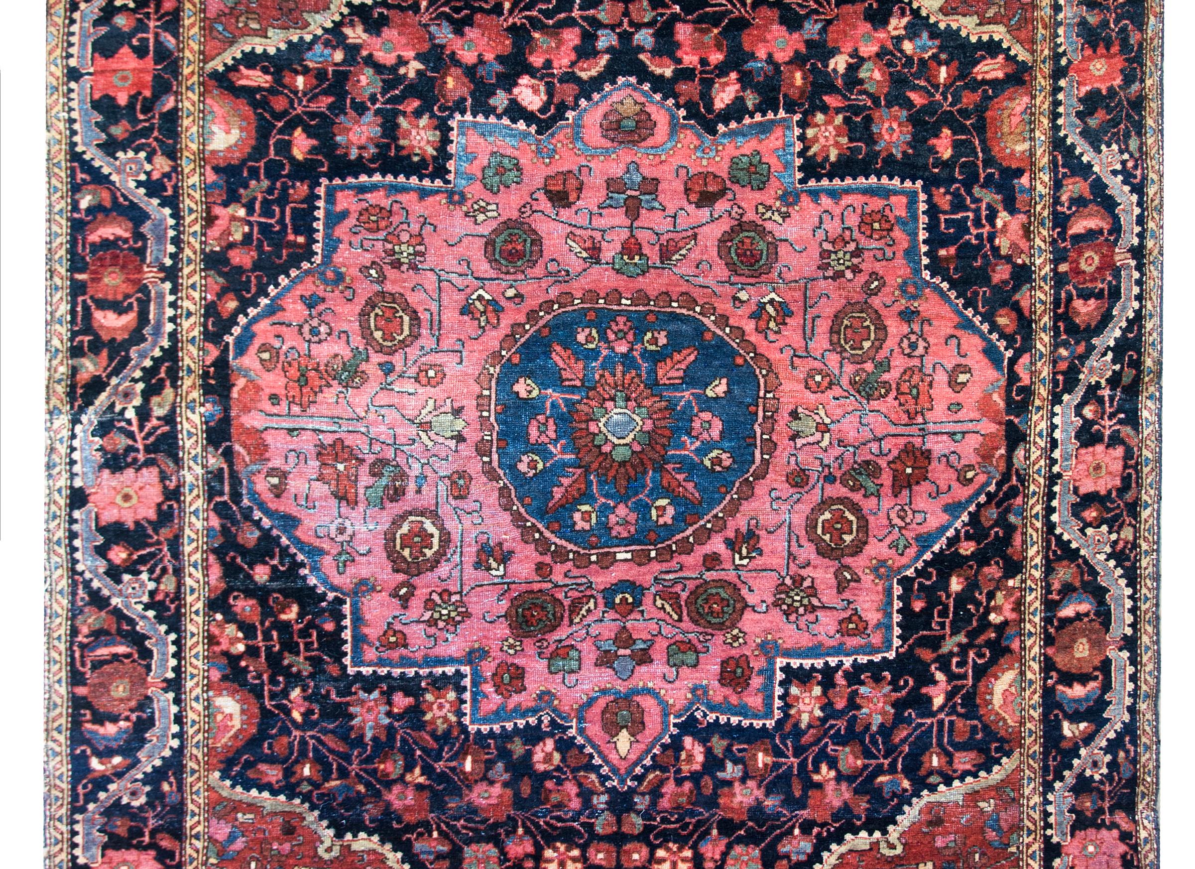 A wonderful early 20th century Persian Sarouk Farahan rug with a large central floral medallion with stylized flowers, leaves, and scrolling vines set amidst a field of more densely woven flowers and vines, all woven in light and dark indigo, pink,