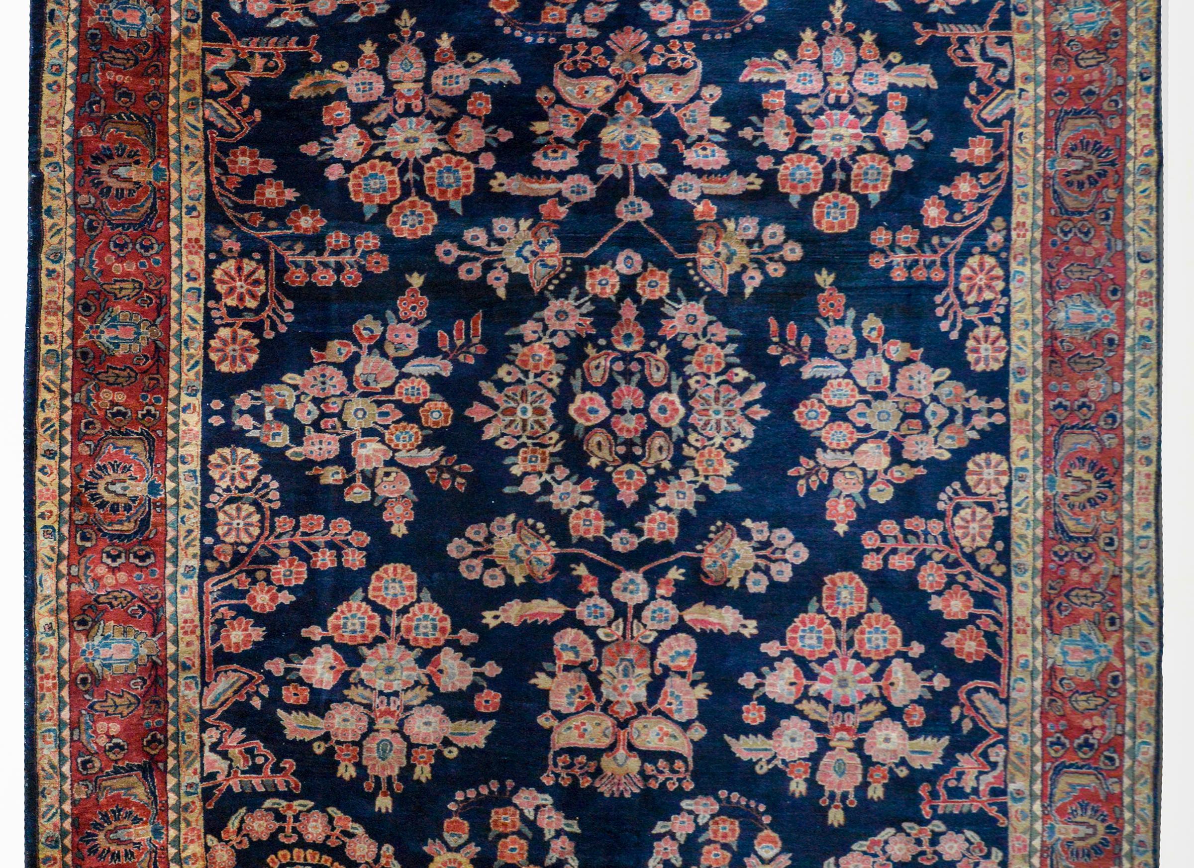 A wonderful early 20th century Persian Sarouk Mohajeran rug with a beautiful all-over mirrored floral pattern woven in traditional Sarouk colors of light and dark indigo, crimson, cream, and pink. The border is outstanding with a wide central floral