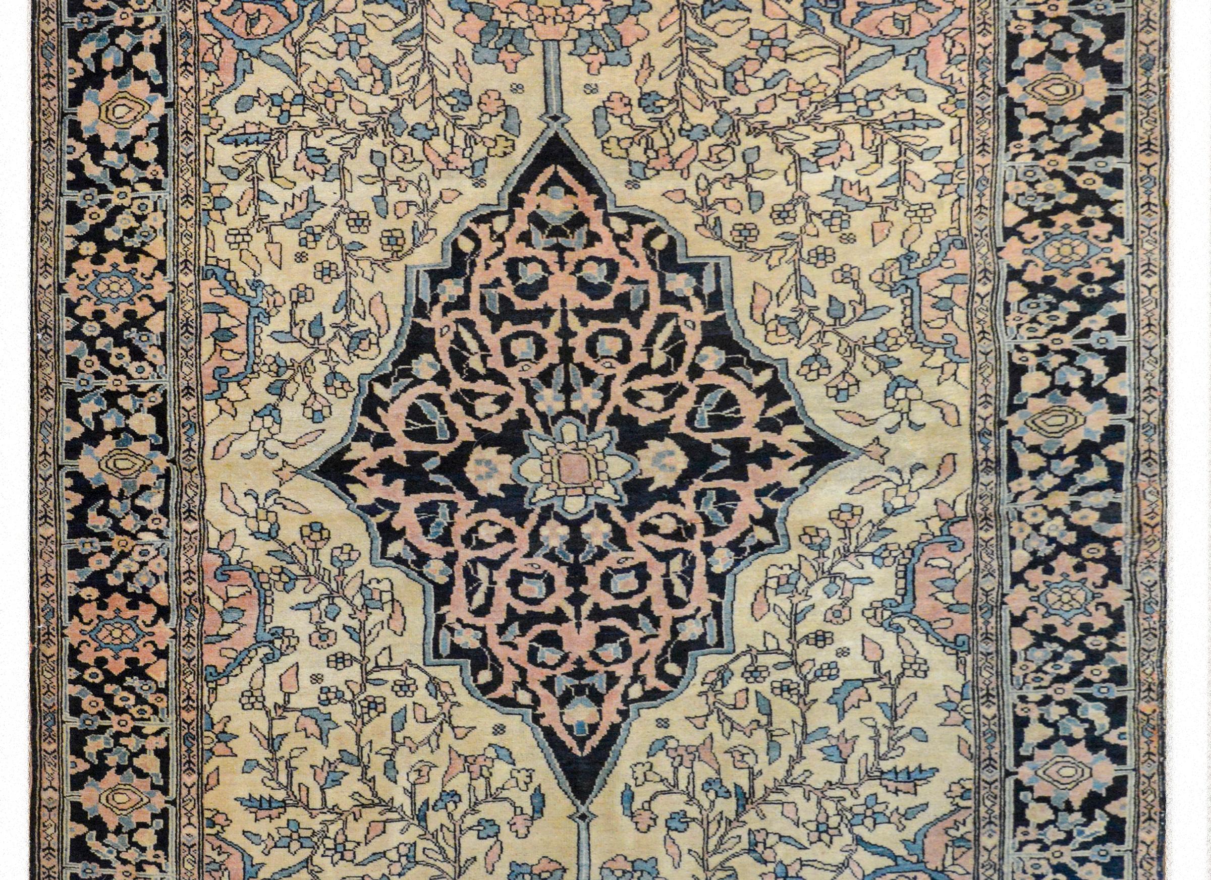 A beautiful early 20th century Persian Sarouk rug with a large central diamond medallion with a pink, gold and light indigo scrolling vine pattern against a dark indigo background, and sitting amidst a pale gold field of more scrolling vines, and