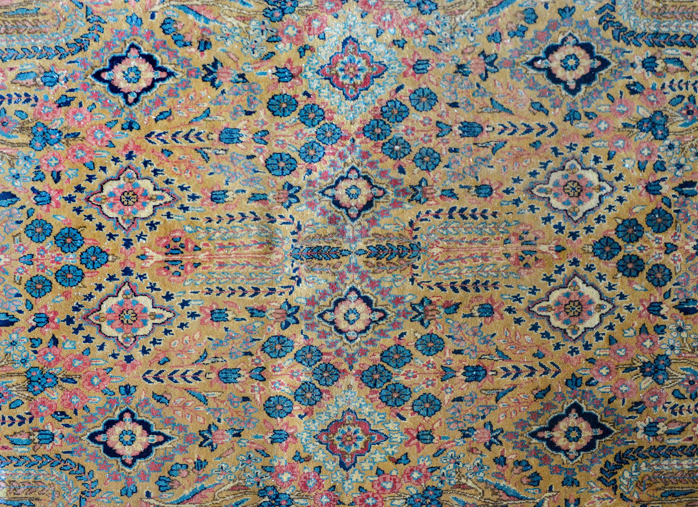 An early 20th century Persian Sarouk rug with a mirrored floral pattern containing myriad willow and cypress trees, flowers, and trees-of-life, all woven in rich golds, blues, pinks, and creams, and surrounded by a wide floral patterned border.