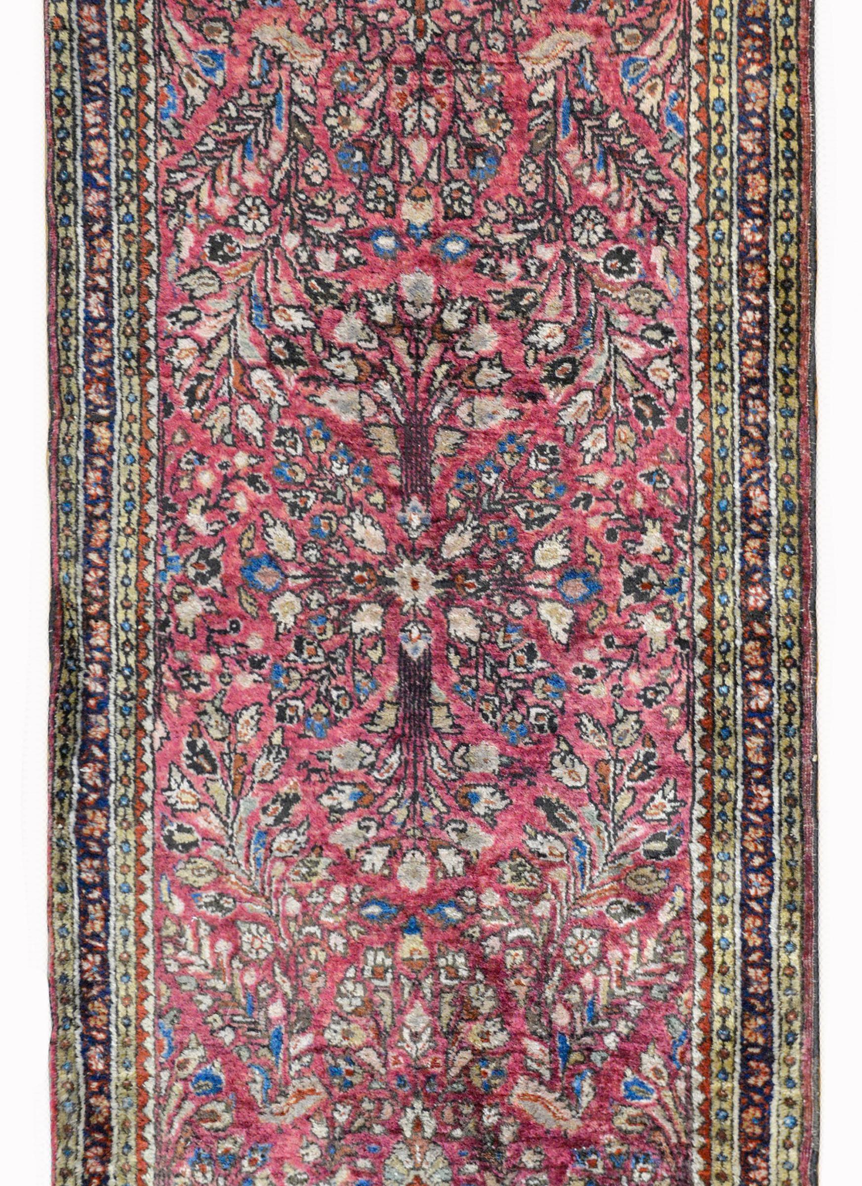 A wonderful early 20th century Persian Sarouk rug with a traditional mirrored floral pattern against a pale cranberry background. The border is composed with multiple geometric and floral patterned stripes.