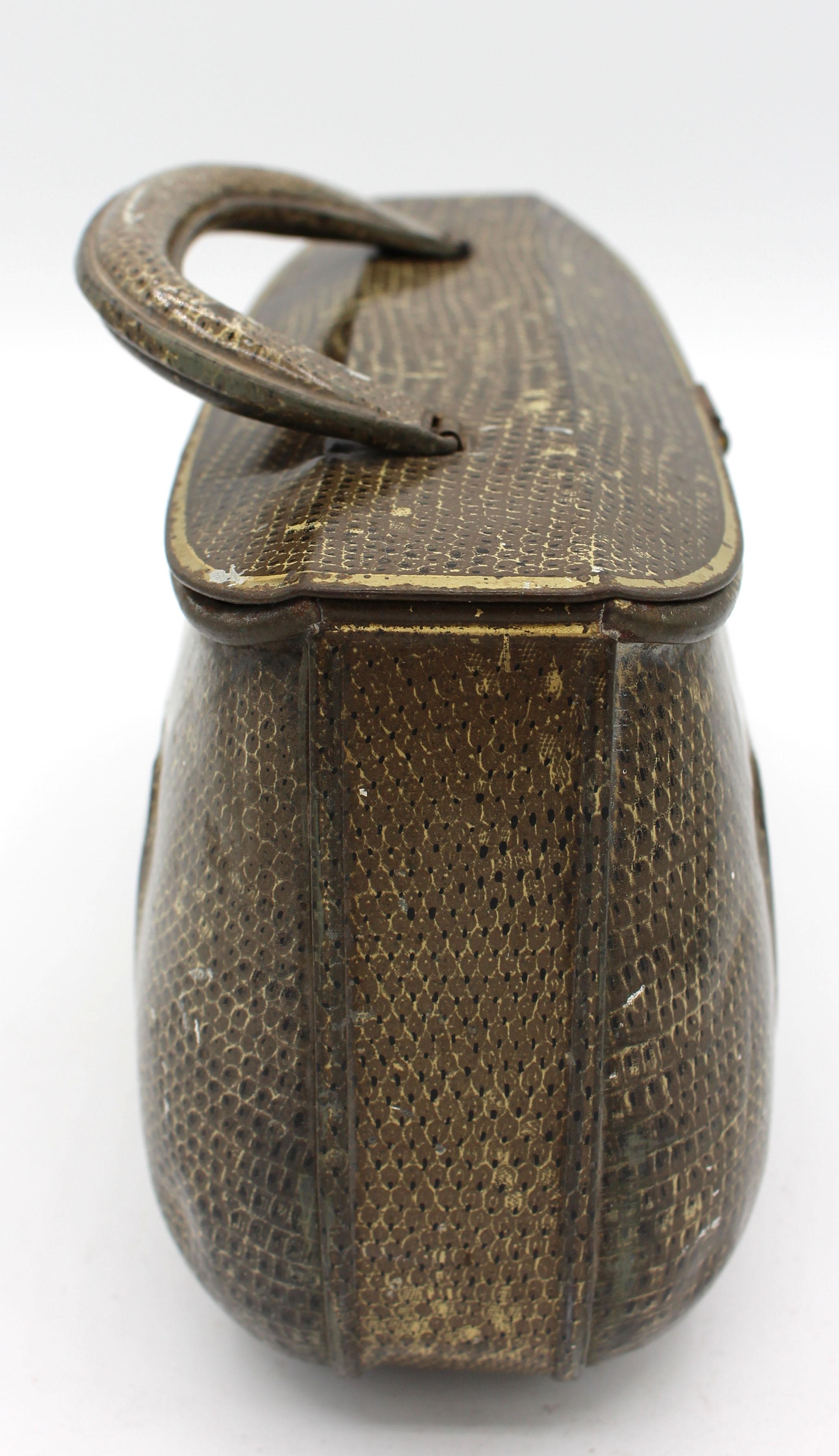 A satchel purse form biscuit tin box by Huntley & Palmers, early 20th century, English. Faux snakeskin decoration with elegant details. Registration No. 48391L, 1908. All parts in good order. Wear to surfaces is commensurate with age & use;