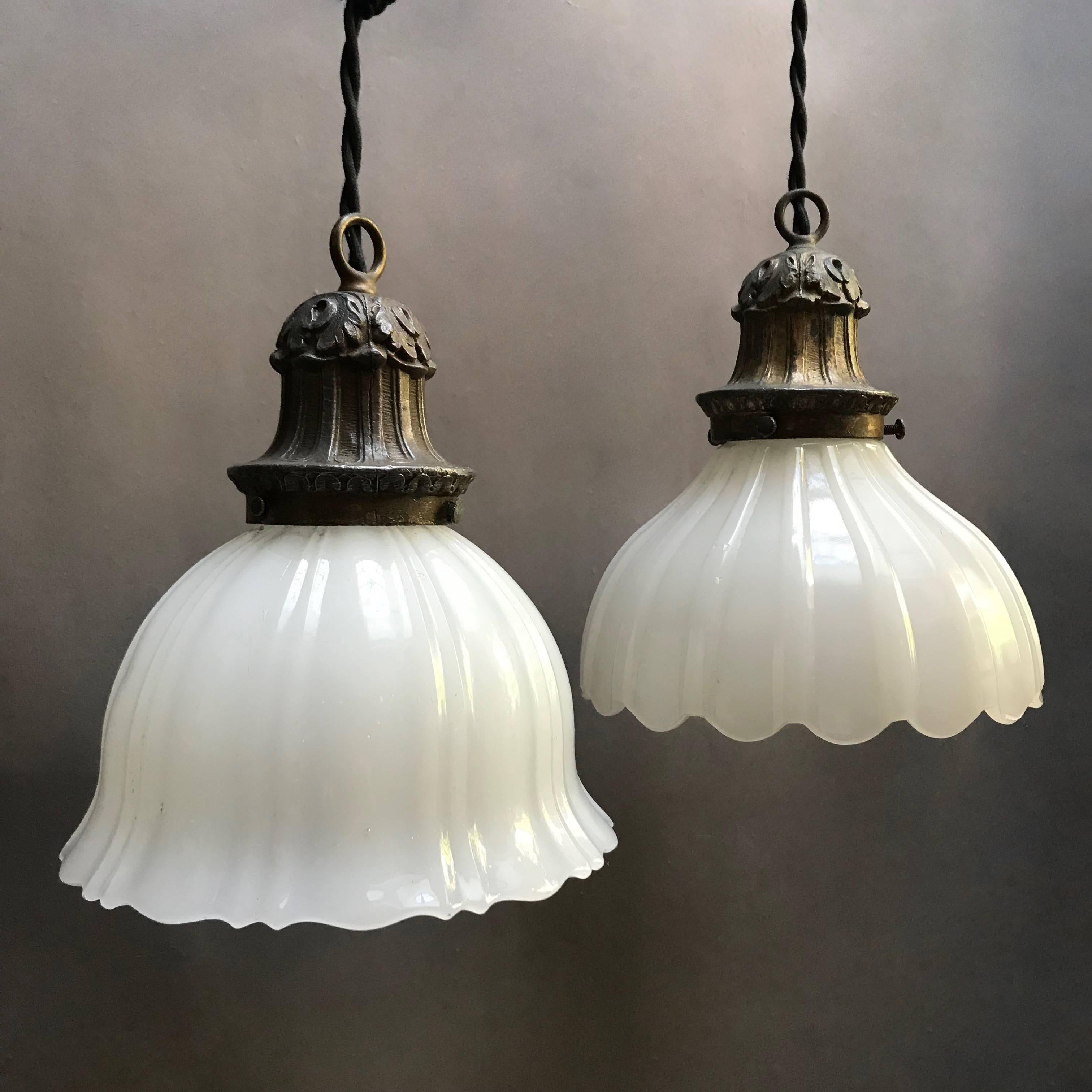 Antique pendant lights feature fluted and scalloped, thick milk glass shades with decorative brass fitters are newly wired with 50 inches of braided black cloth cord to accept 150 watt bulbs each. The shades vary so they are sold separately but they