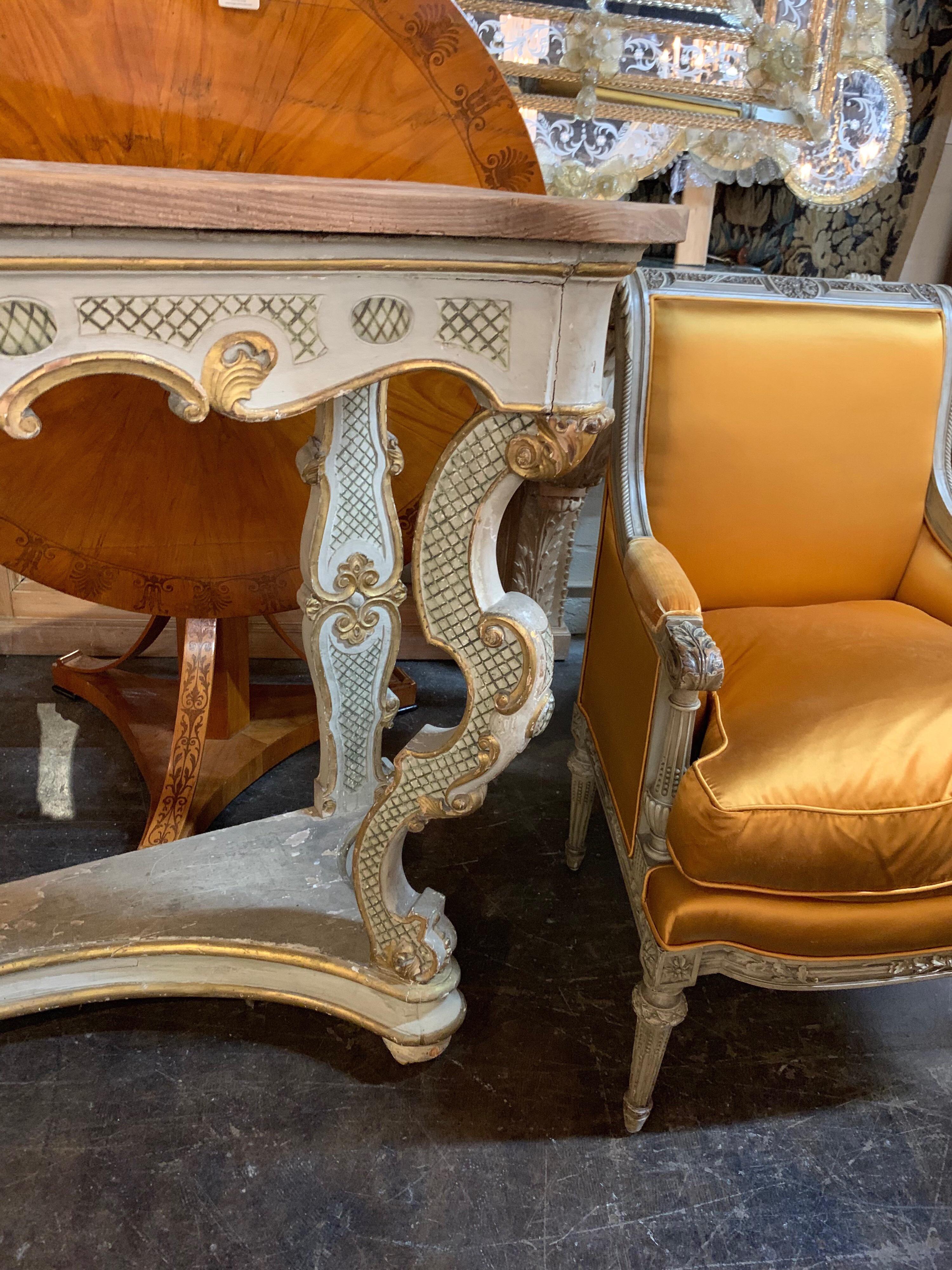 Beautiful carved console table that is painted in a grey color with a parcel-gilt. A very interesting look that could be mixed in with a variety of styles. Also note the height. This piece is taller than most console tables.