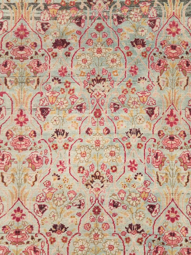 An antique Persian Mashad room size carpet from the early 20th century with an intricate Millefleur pattern in both the seafoam green field and ruby red border.

Measures: 8' 6