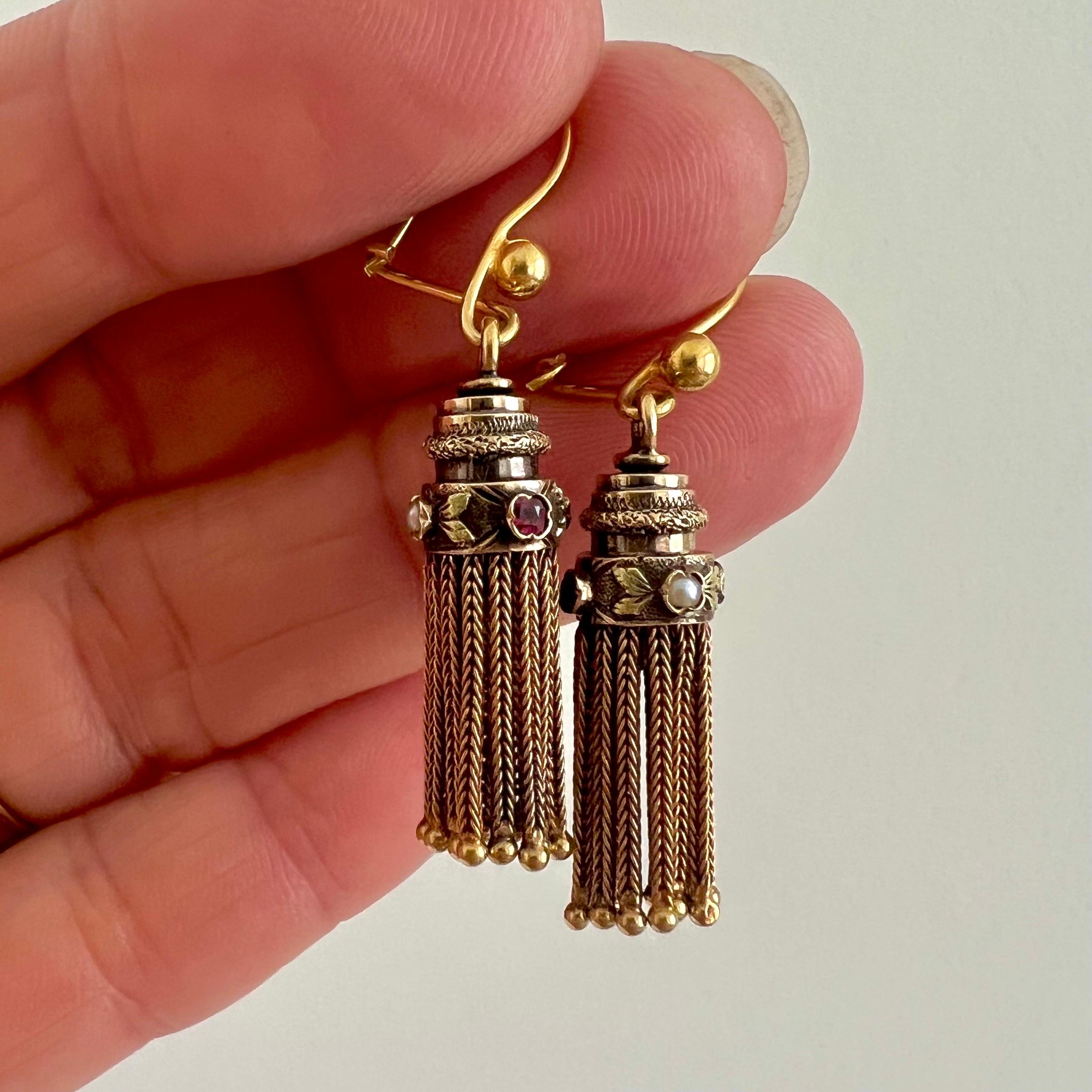 A lovely and ornate pair of antique tassel earrings, crafted in 14 karat yellow gold and enriched with delicate seed pearls and vibrant synthetic rubies. These earrings embody both refinement and playful movement.

Each earring is set with two seed