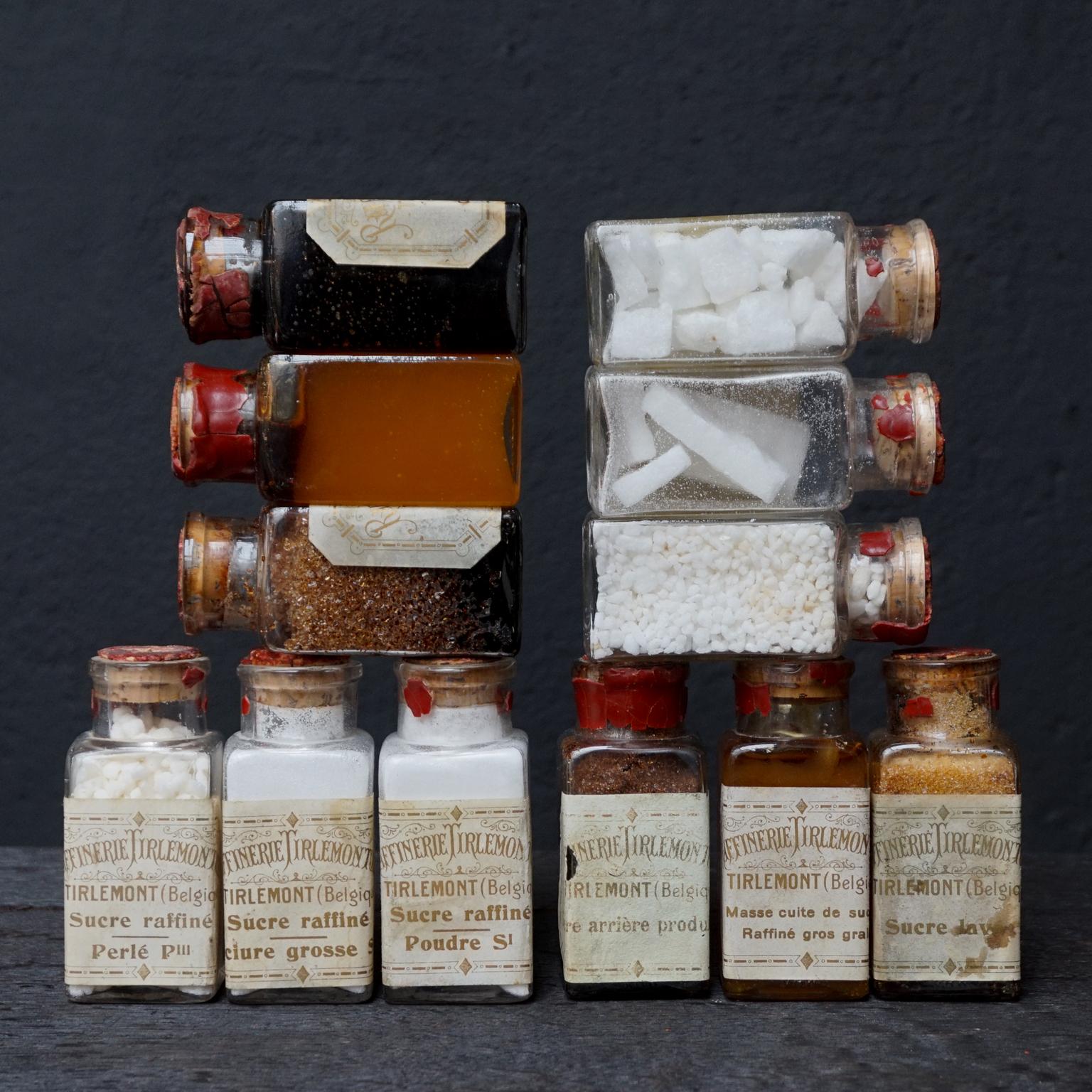 An early 20th century selection of 18 glass vials sugar samples, filled with different forms and stages of sugar. The glass containers are closed with cork stoppers and sealed with seal-wax stamped with the text: 
