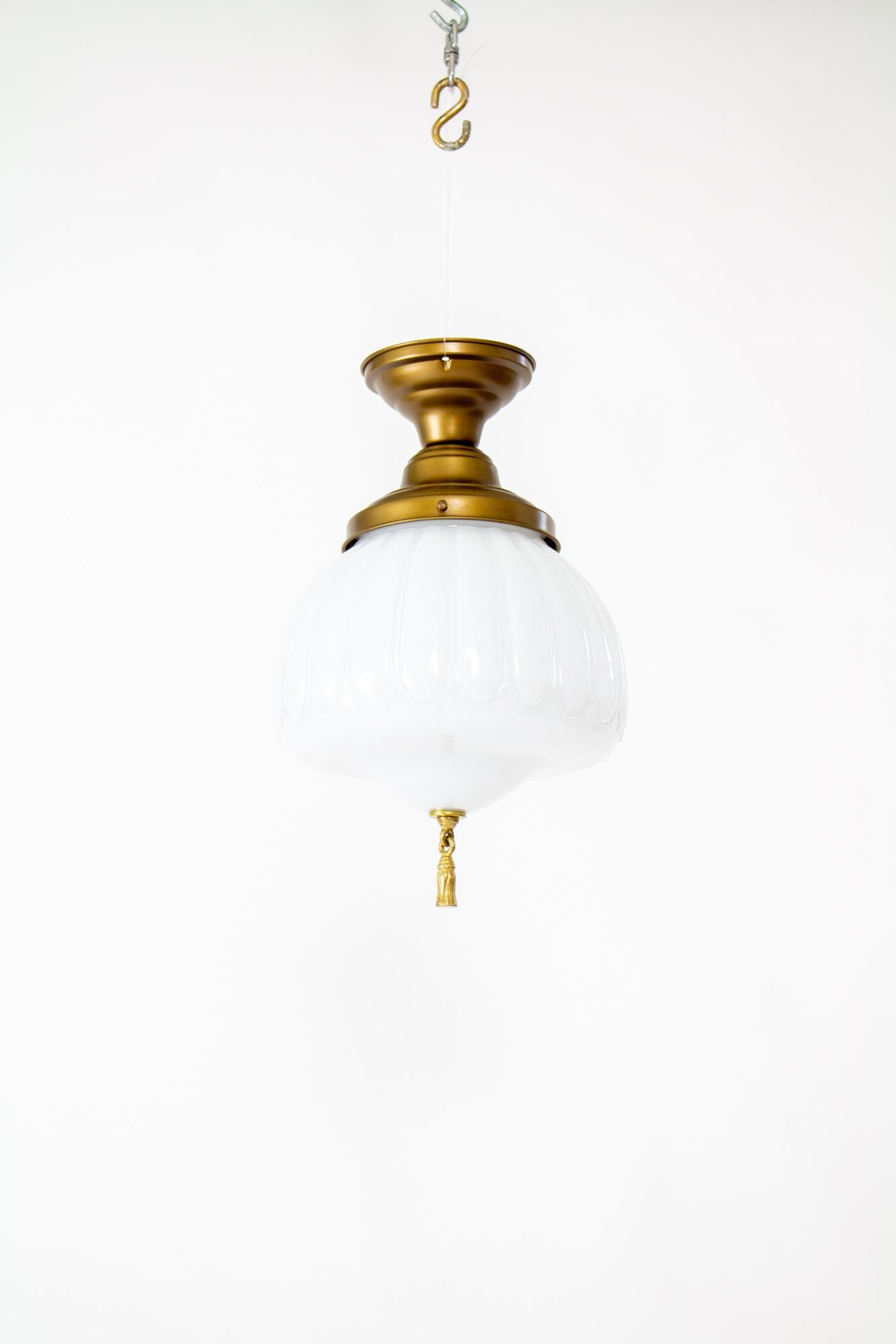 Early 20th Century semi flush white case glass fixture with bronze tassel. Early 20th century glass in a round pillowed shape with a bottom tassel, white case glass. Fixture is new in a bronze finish. Glass in good condition with some light chips