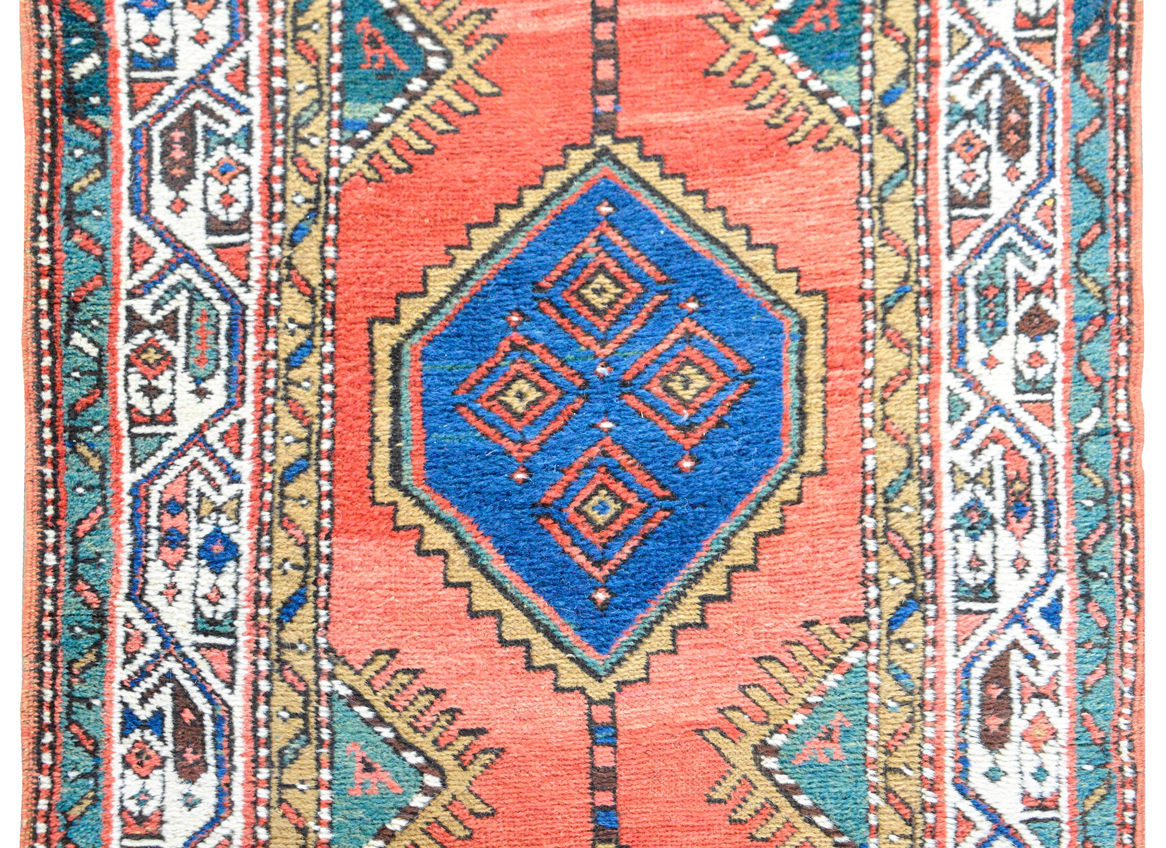 A beautiful and striking early 20th century Persian Serab runner with several indigo diamond medallions each with stylized geometric flowers in the center, and living against a crimson background. The border is wonderful with a stylized scrolling